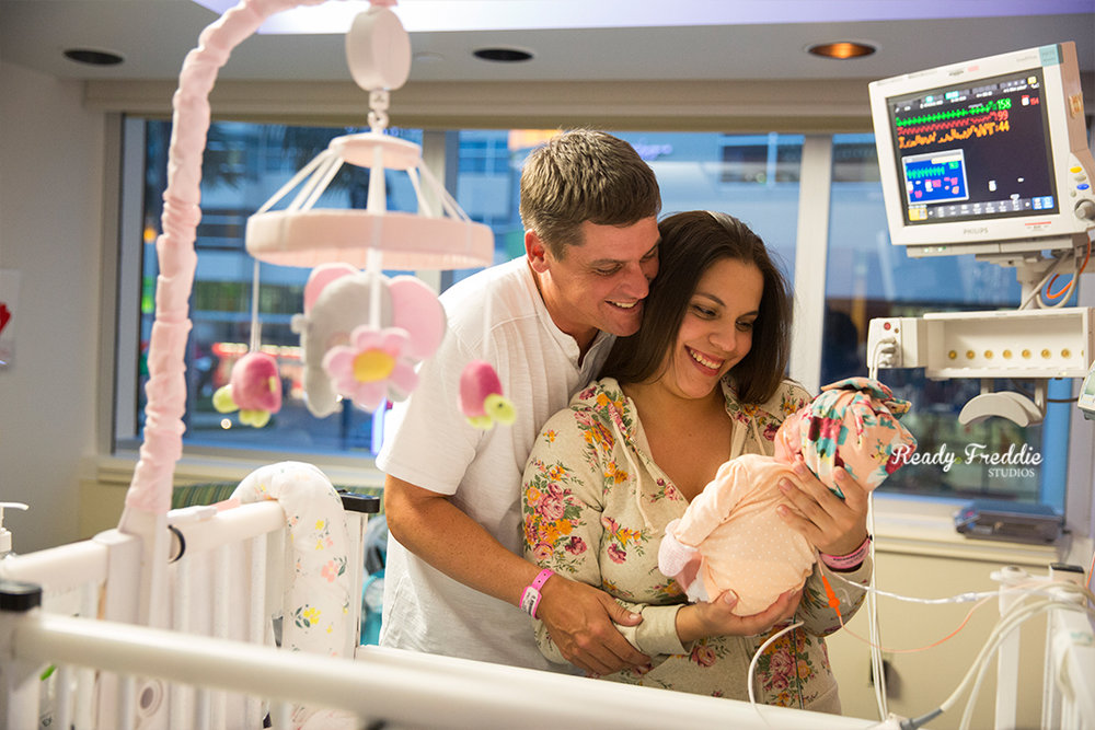 Parents in the prenatal ICU smiling and holding their premie baby girl at baptist South Miami Hospital.