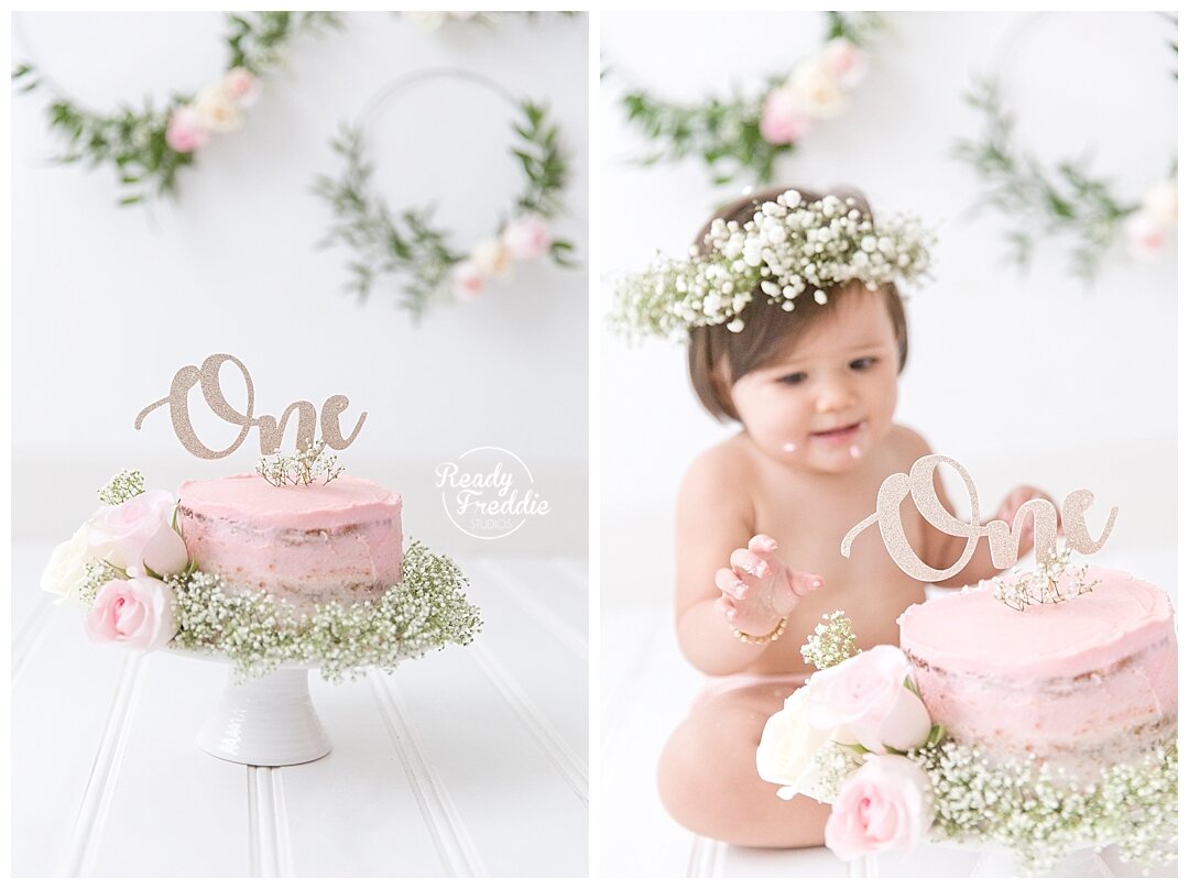 Pink frosted cake with a "ONE" cake topper and baby breath around the cake to match the baby breath floral crown for cake smash session in Miami by Ivanna Vidal Photography