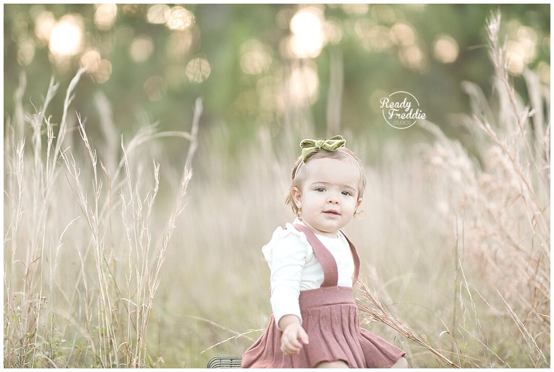 One year old girl at the field with pink dress | Ready Freddie Studios in Miami, FL