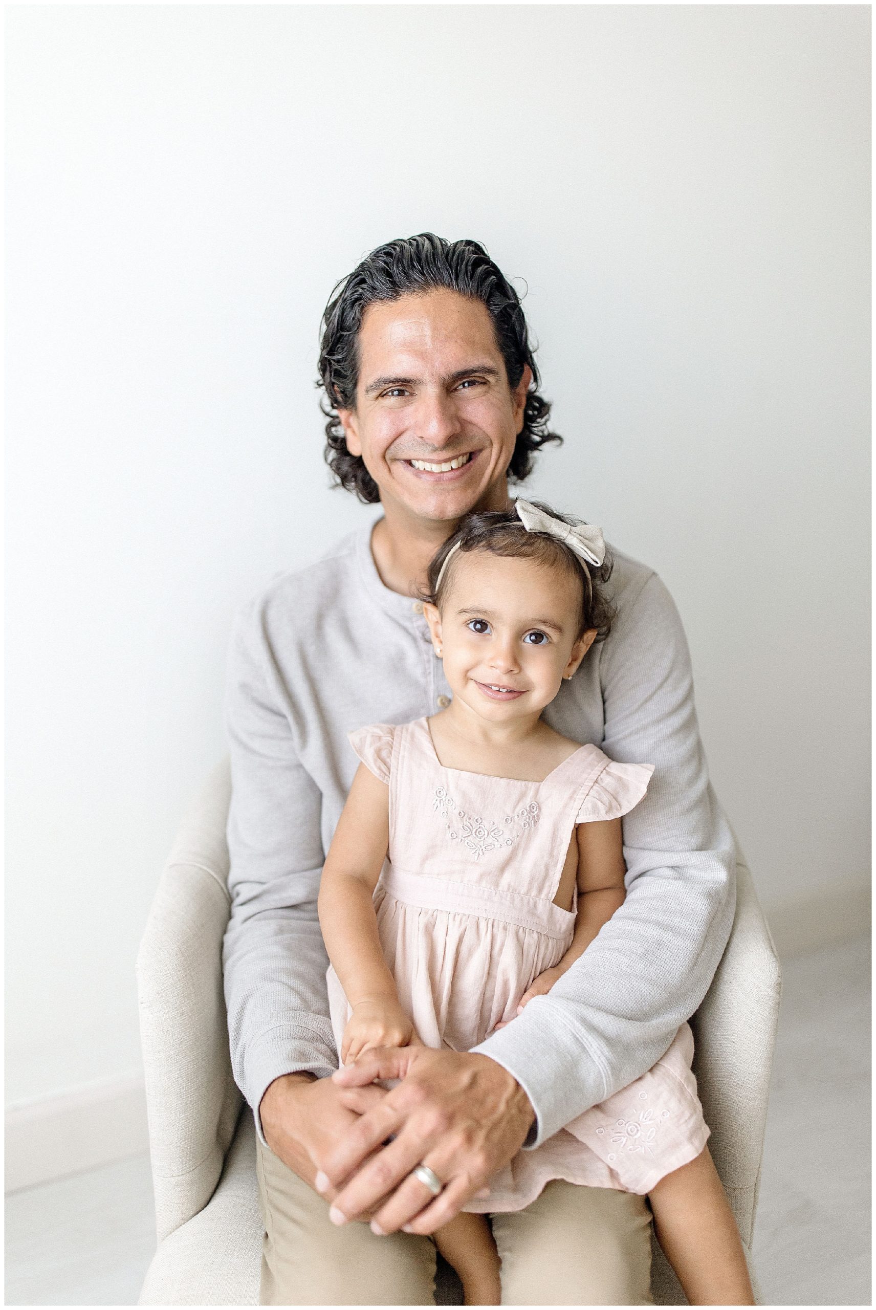 Daughter sits in dad's lap for portrait. Photo by Ivanna Vidal Photography.