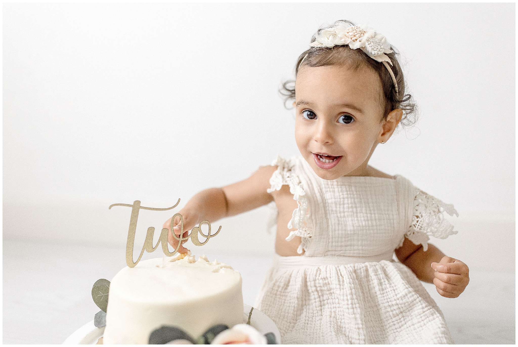 Child dips their fingers into white smash cake. Photo by Ivanna Vidal Photography.