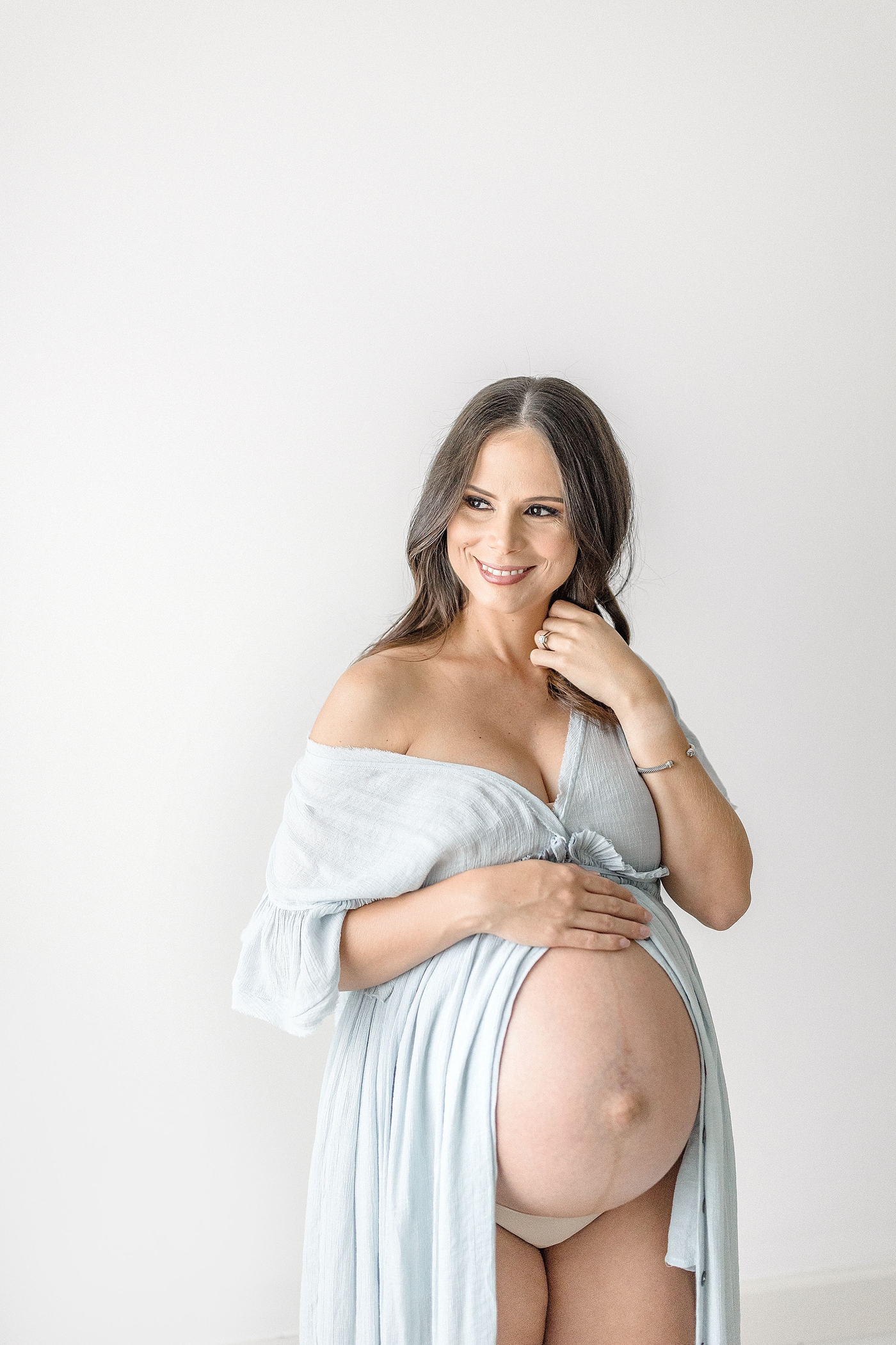 Glowing mama smiles during maternity session in studio. Photo by Ivanna Vidal Photography.