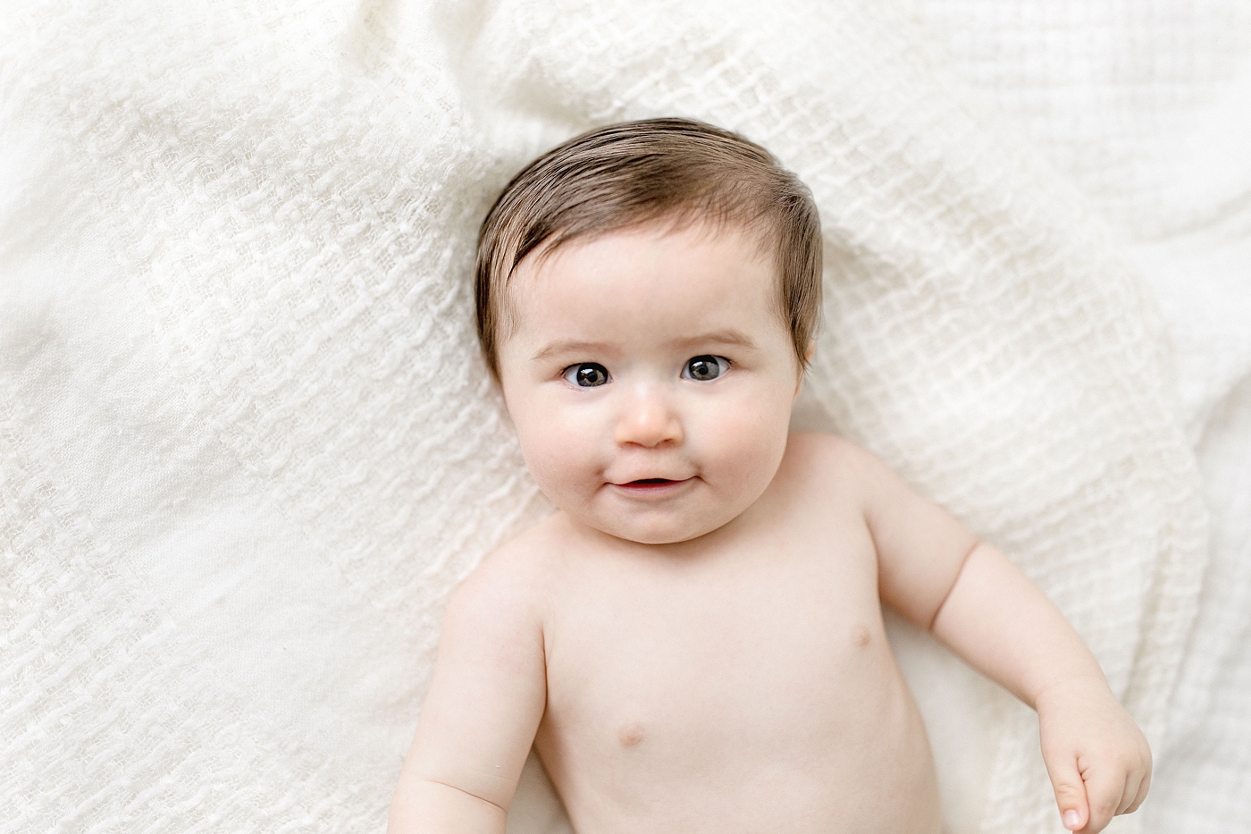 Baby boy lays on white blanket with Miami Children Photographer. Photo by Ivanna Vidal Photography.