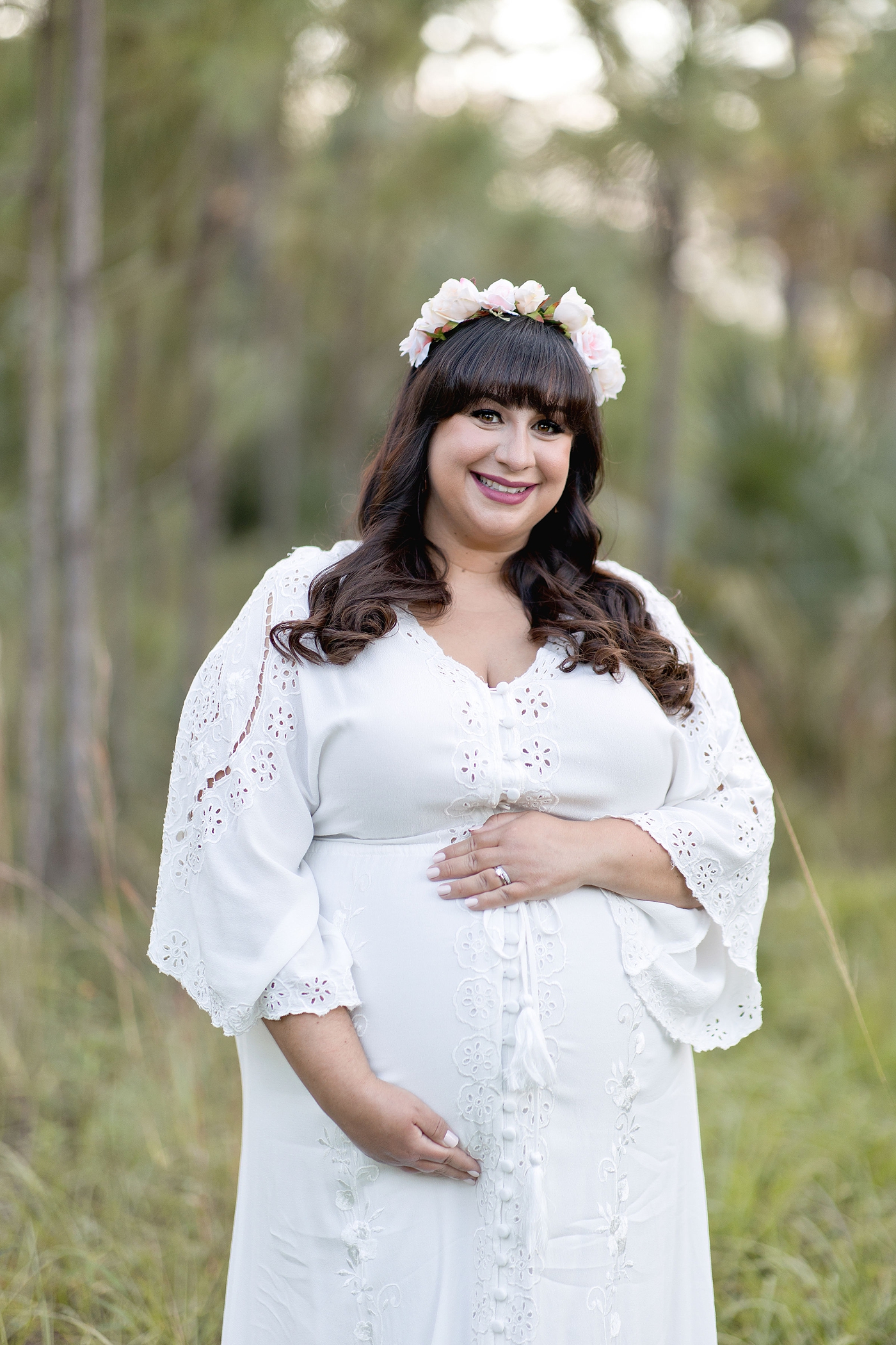 Pregnant mom smiles at camera while holding her belly. Photo by South Florida Maternity Photographer Ivanna Vidal Photography.
