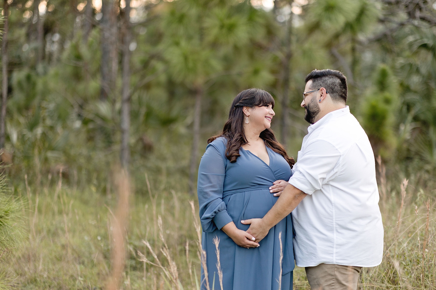 Plus Size Maternity Photoshoot with Mom and dad look lovingly into one another's eyes. Photo by South Florida Maternity Photographer Ivanna Vidal Photography.