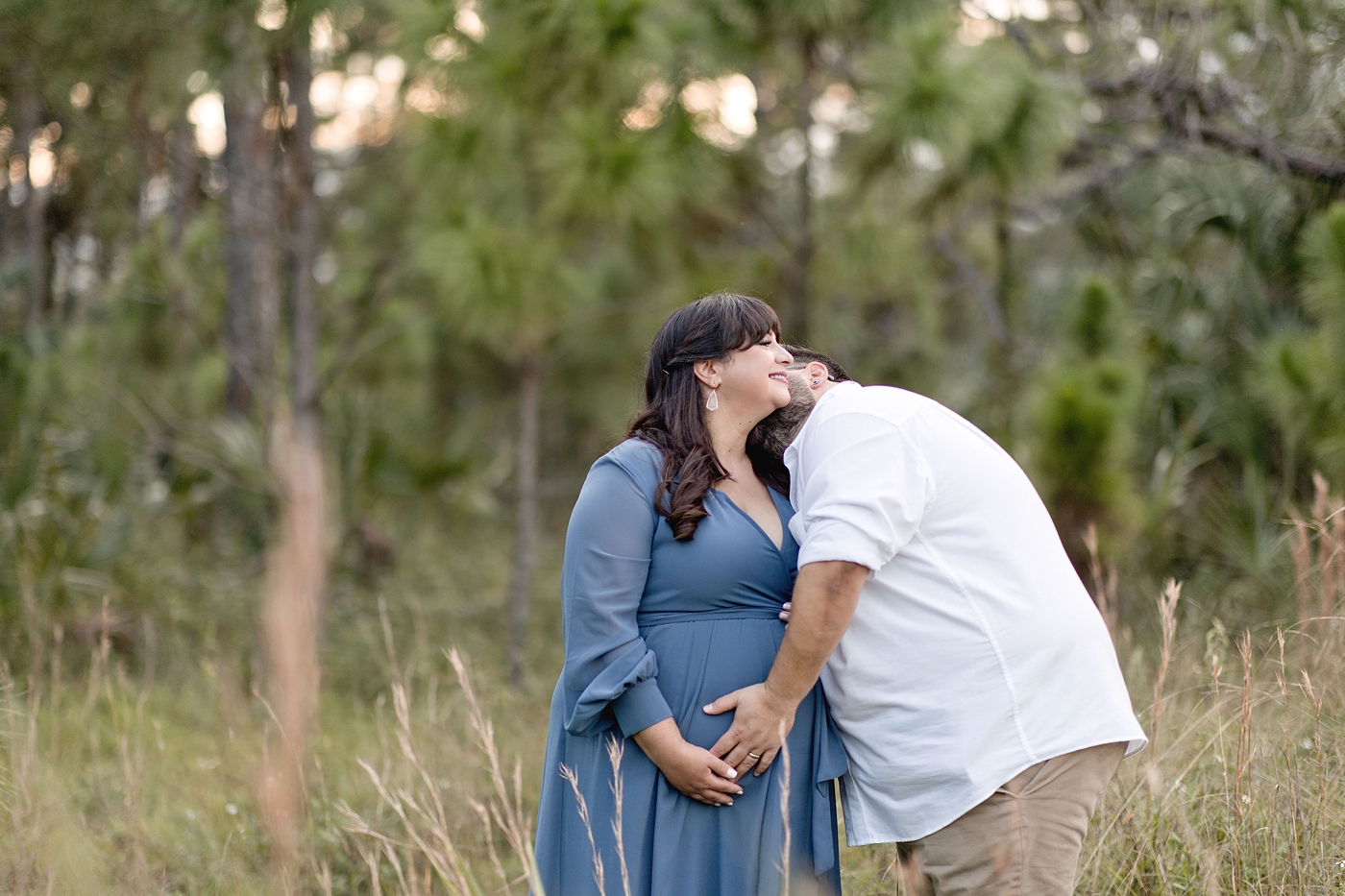 Dad kisses mom on the neck during mother nature inspired maternity session. Photo by South Florida Maternity Photographer Ivanna Vidal Photography.