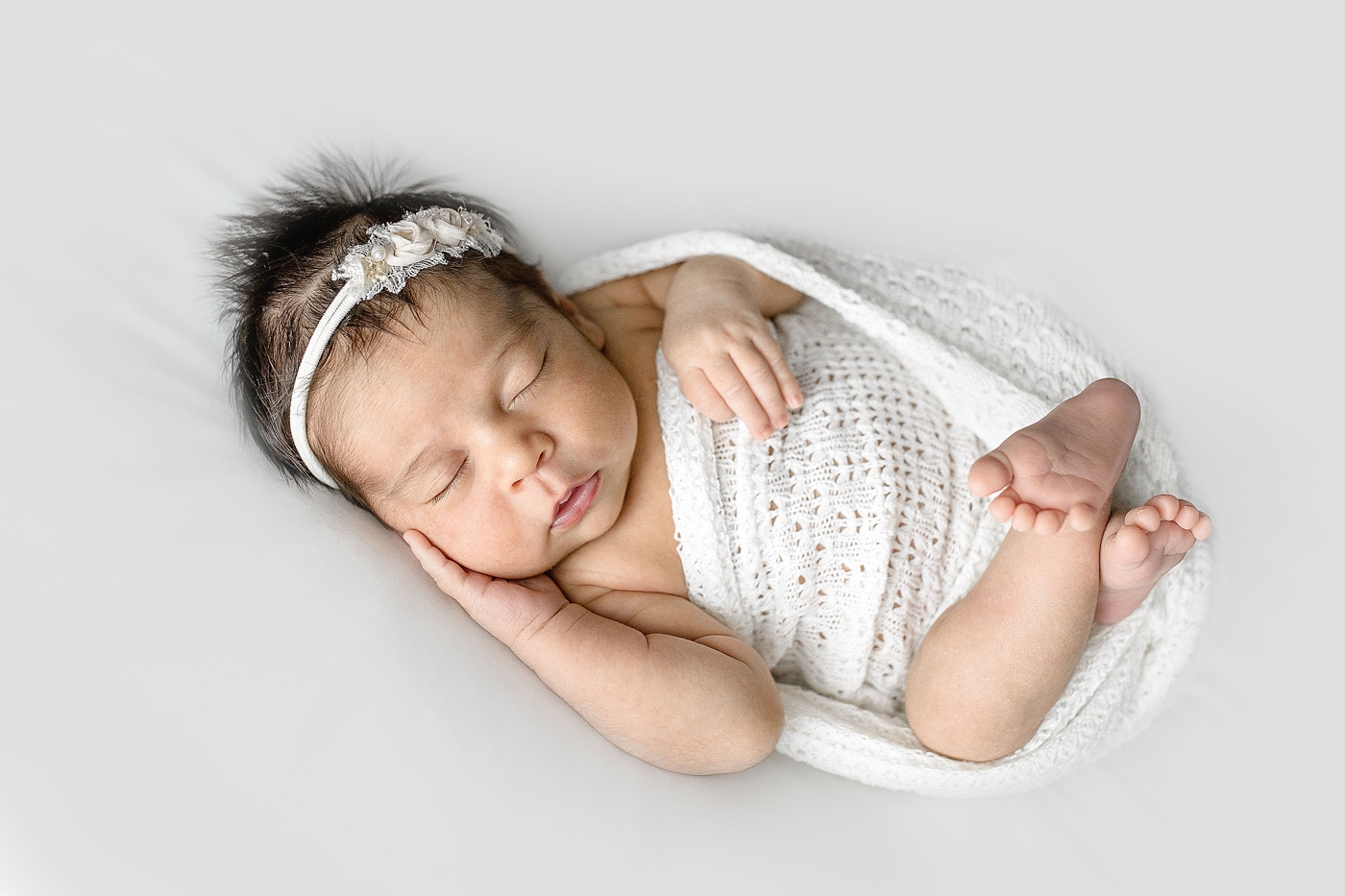 Baby wrapped in white lace swaddle during Newborn Photography Miami session. Photo by Ivanna Vidal Photography.