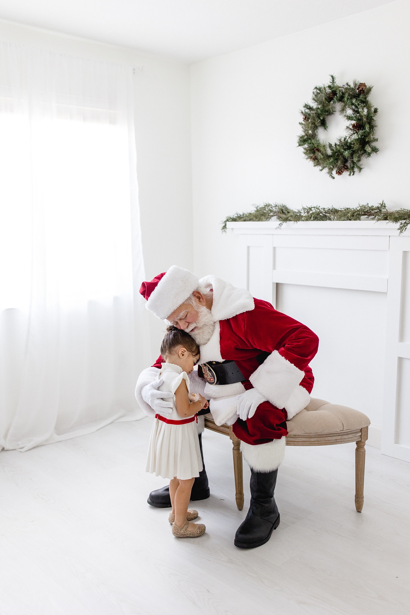 Little girl hugs Santa Claus during Miami studio session. Photo by Ivanna Vidal Photography.