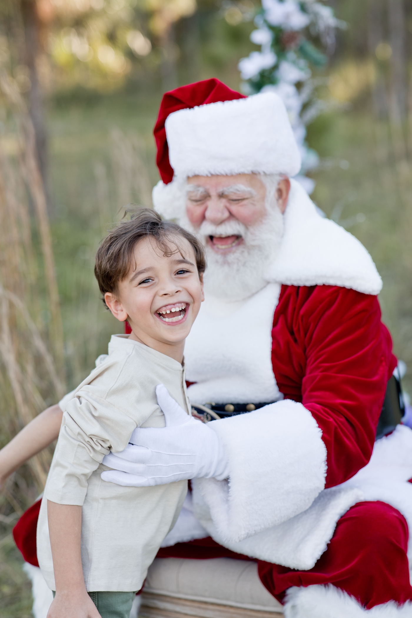 Santa and little boy laugh together. Photo by Ivanna Vidal Photography.