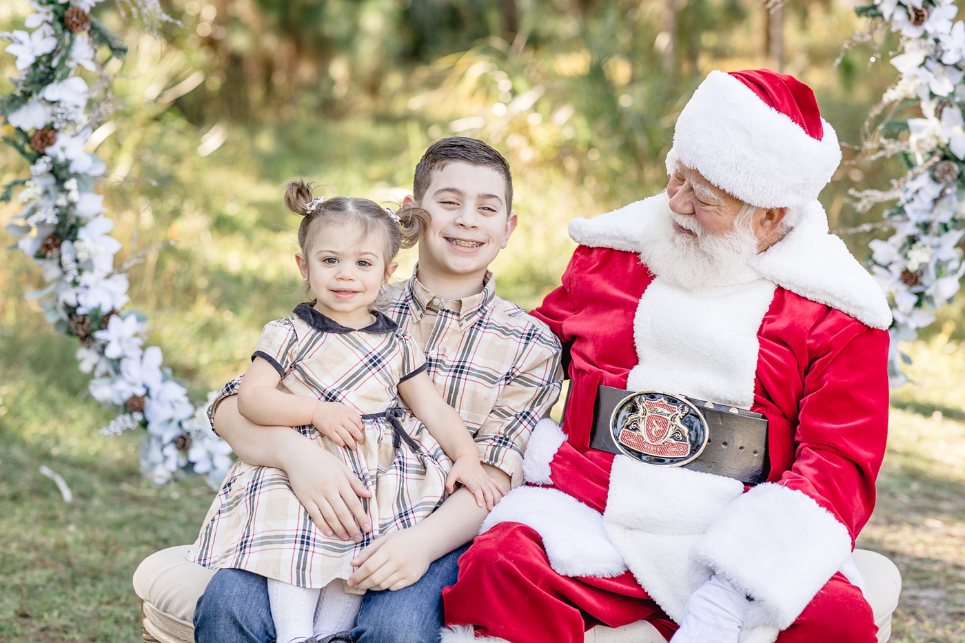 Brother and sister sit next to Santa Claus during Miami Santa session. Photo by Ivanna Vidal Photography.