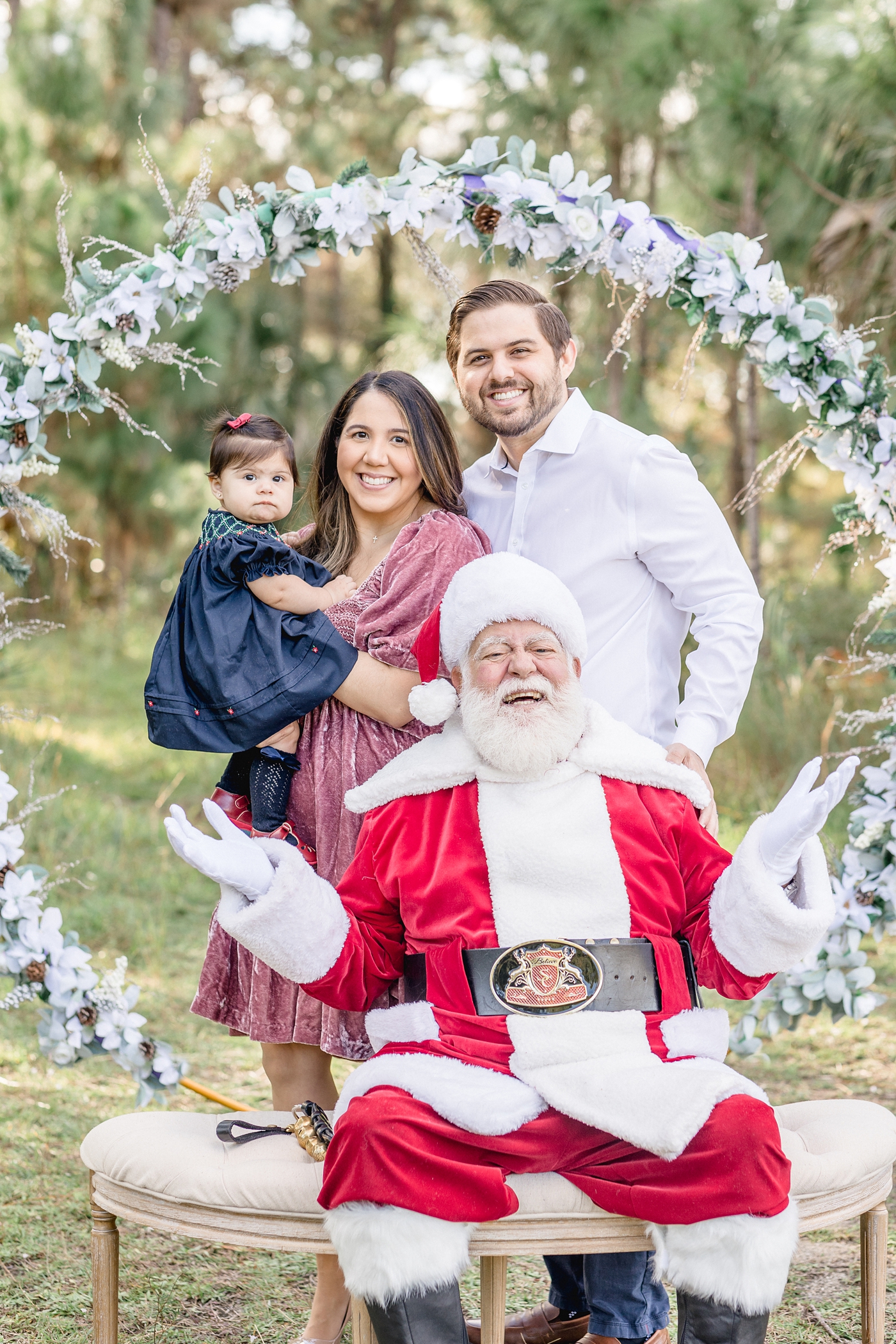 Family stands with Santa Claus during outdoor Miami studio session. Photo by Ivanna Vidal Photography.
