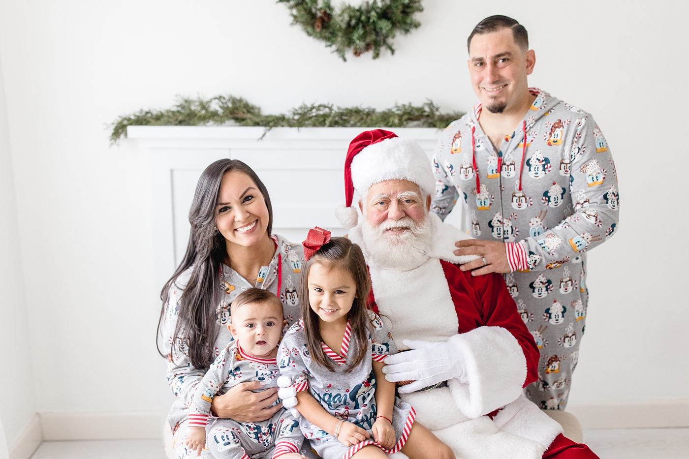Family of four in matching pajamas with Santa Claus studio miami session. Photo by Ivanna Vidal Photography.
