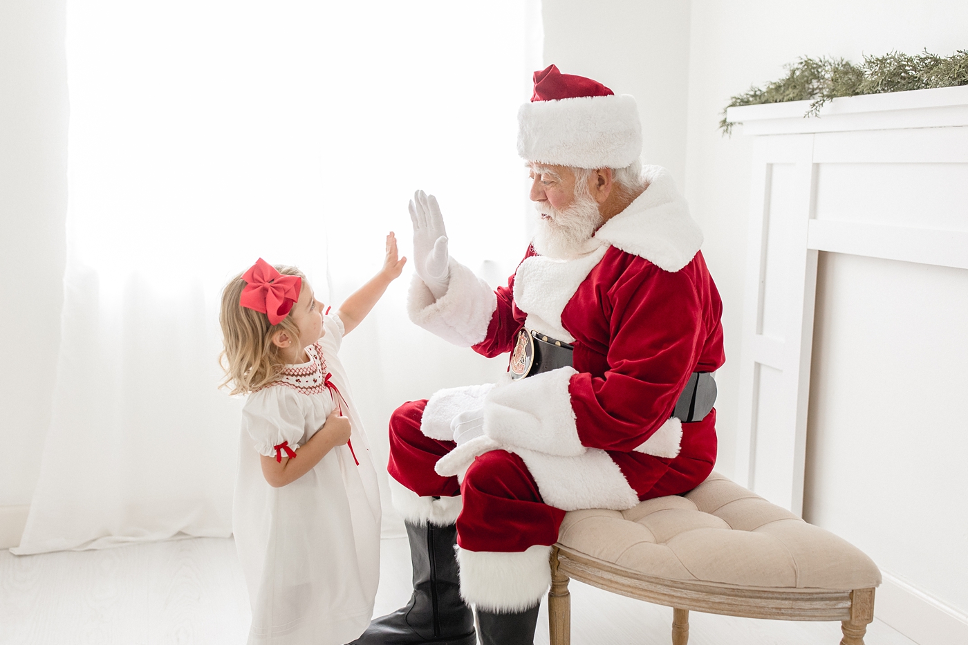 Little girl high fives Santa Claus during Miami studio session. Photo by Ivanna Vidal Photography.