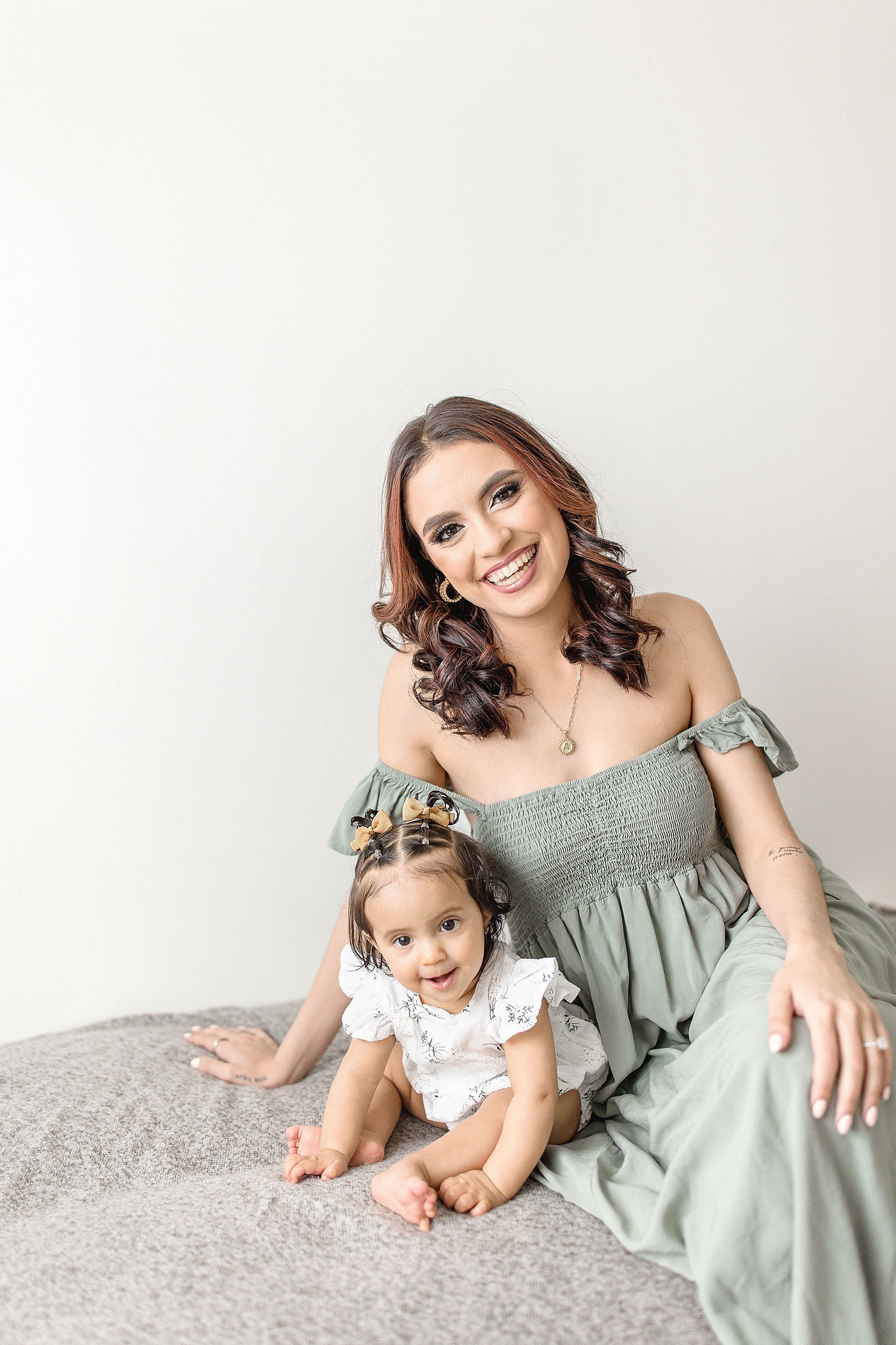 Mom and baby girl sit on bench smiling during baby photography miami session. Photo by Ivanna Vidal Photography.