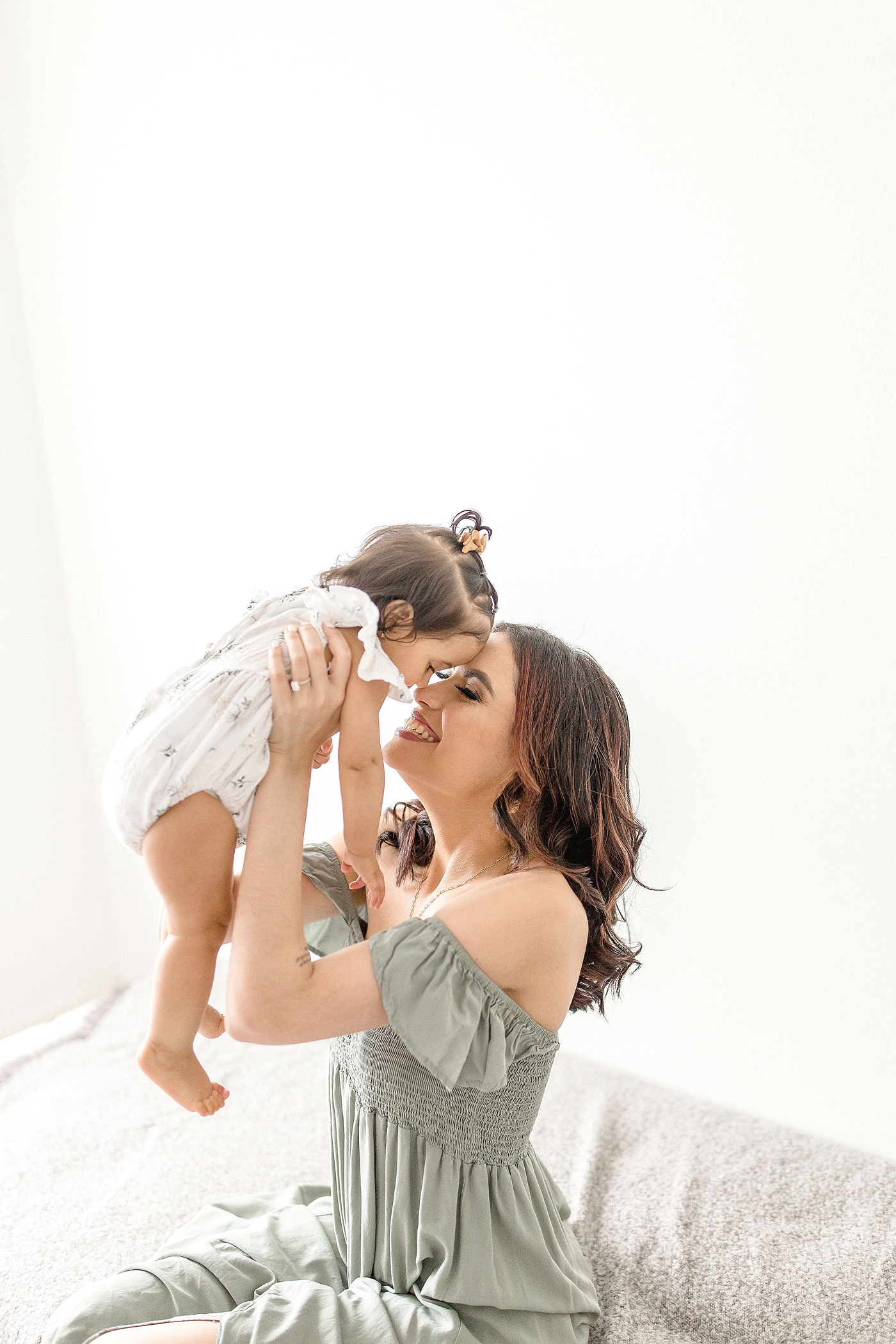 Mom holds up baby girl in the air and nuzzles her nose during baby photography miami session. Photo by Ivanna Vidal Photography.