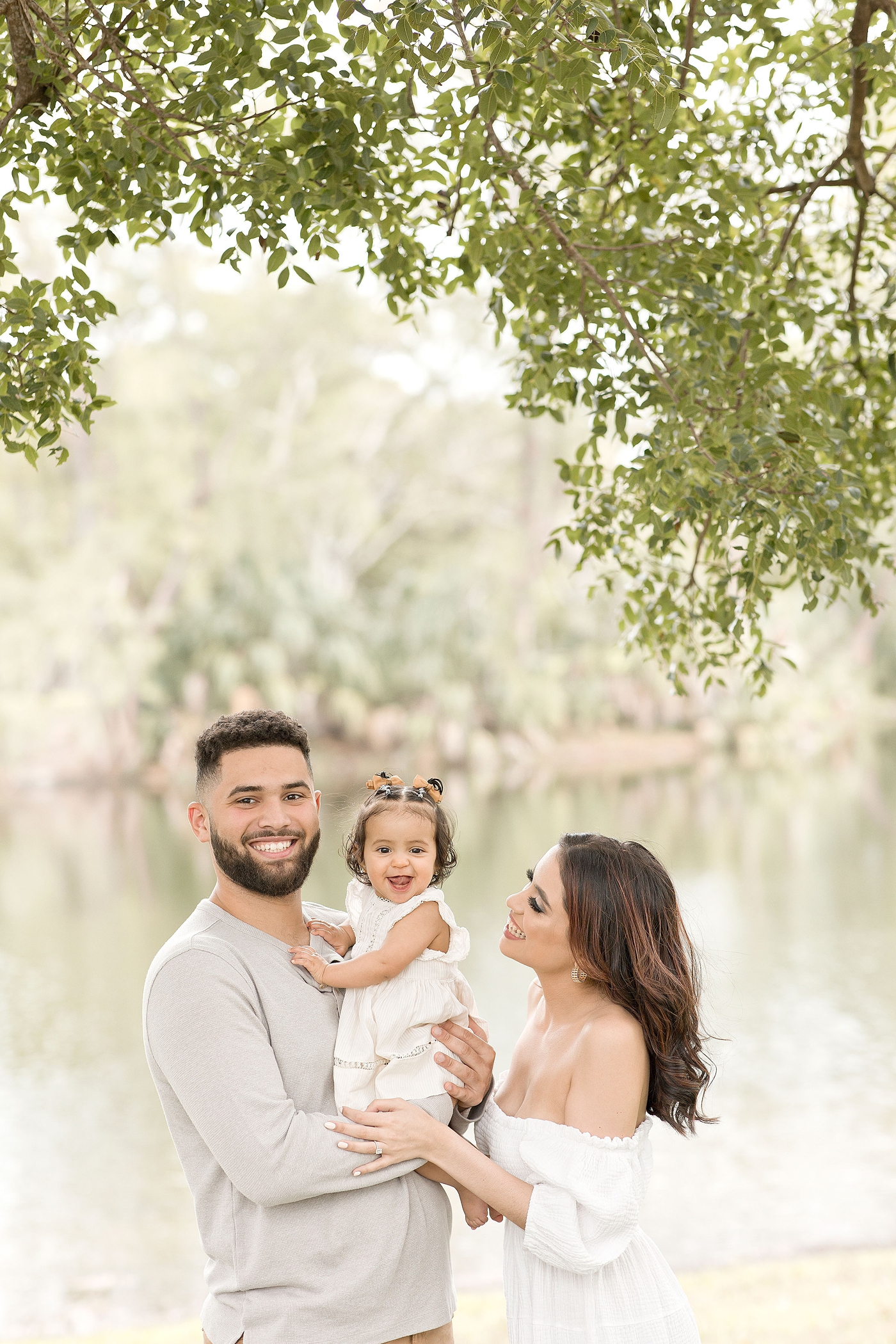 Dad and baby smile while mom lovingly looks at baby girl during baby photography miami session. Photo by Ivanna Vidal Photography.