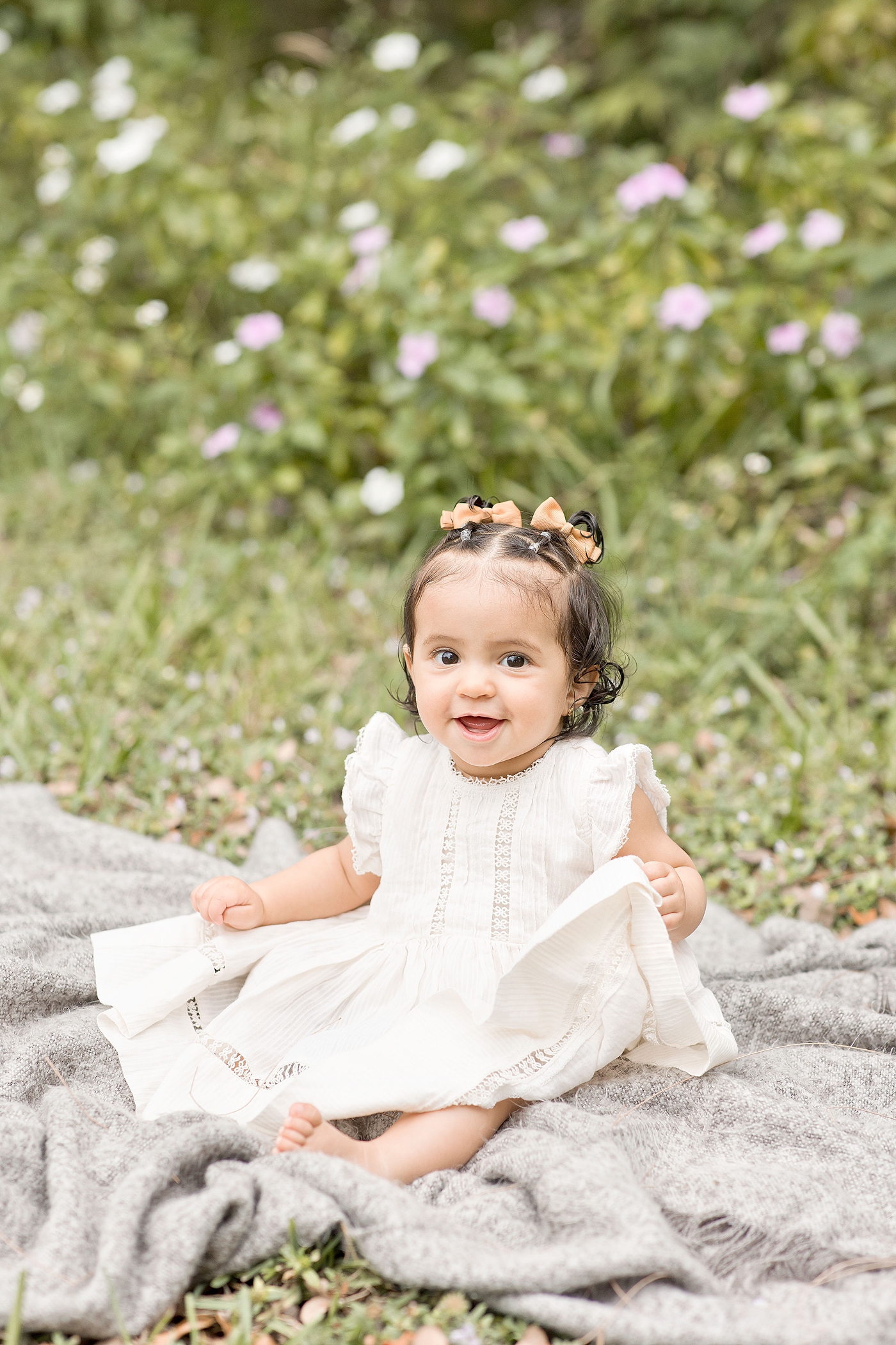 Baby girl smiles while sitting atop a blanket during baby photography miami. Photo by Ivanna Vidal Photography.