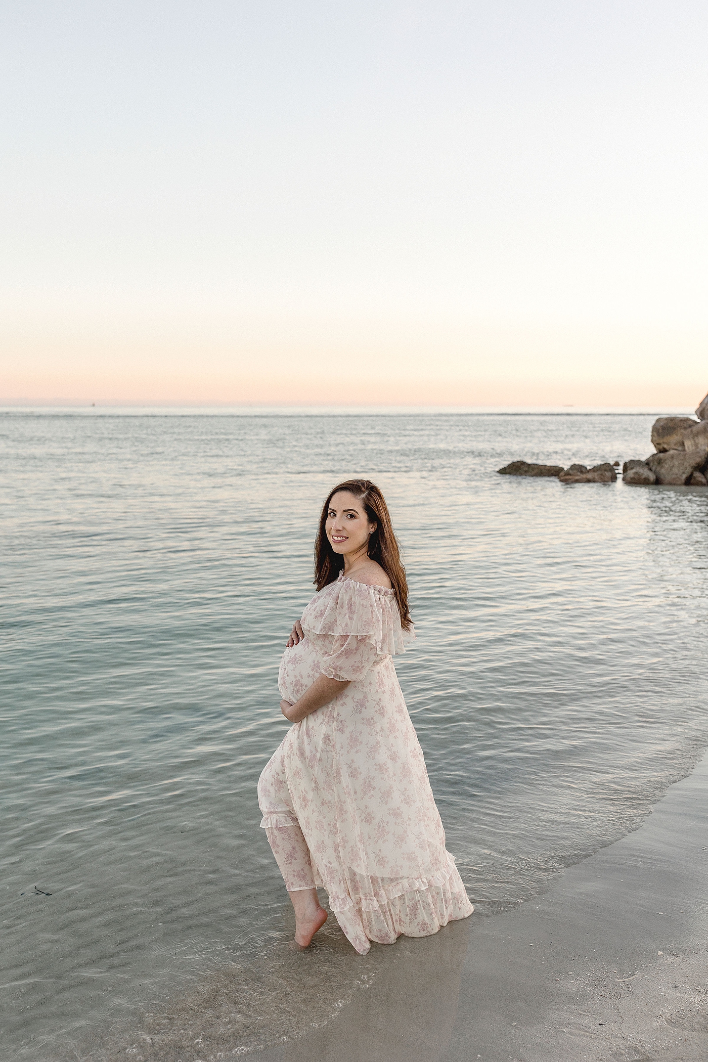 Expectant mom dips her toes in the clear Miami waters during El Farito Beach Miami FL maternity session. Photo by Ivanna Vidal Photography.