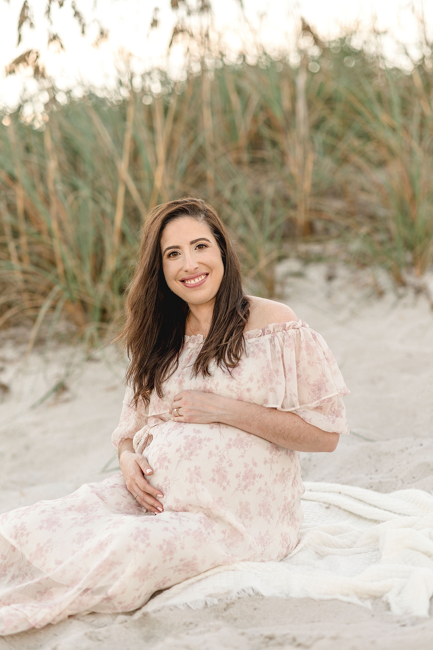 Mom to be sits atop blanket during maternity session at El Farito Beach Miami FL. Photo by Ivanna Vidal Photography.