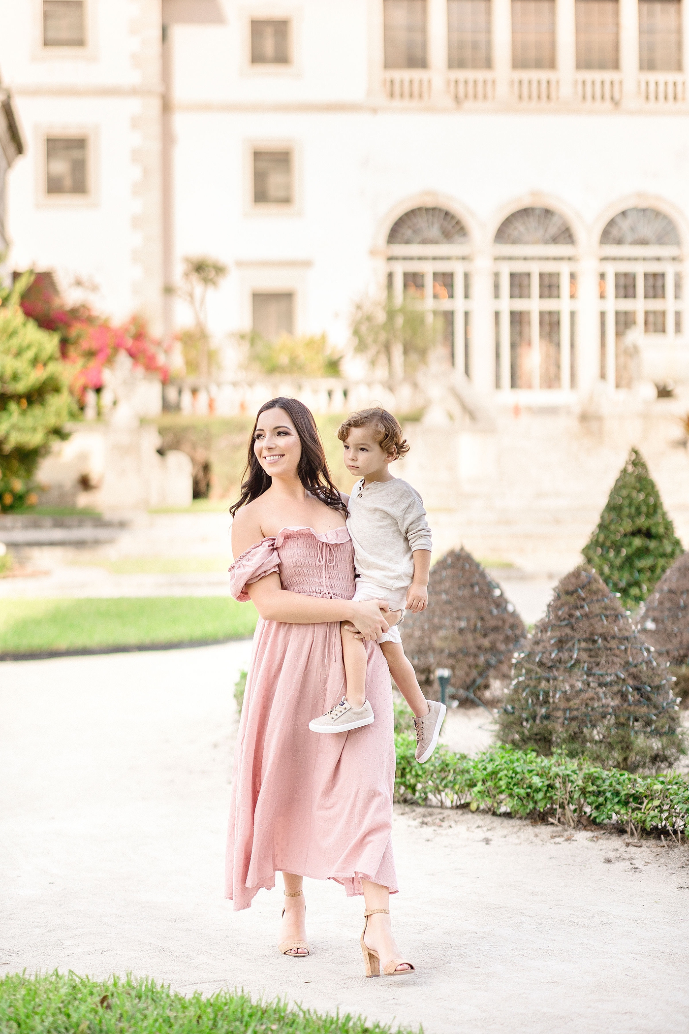 Mom holds son while walking along path in Vizcaya Gardens. Photo by Ivanna Vidal Photography.
