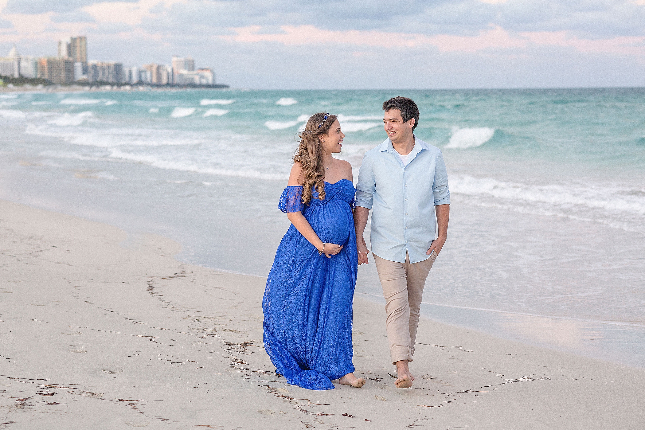couple walking down the beach for their maternity photos after miami prenatal yoga