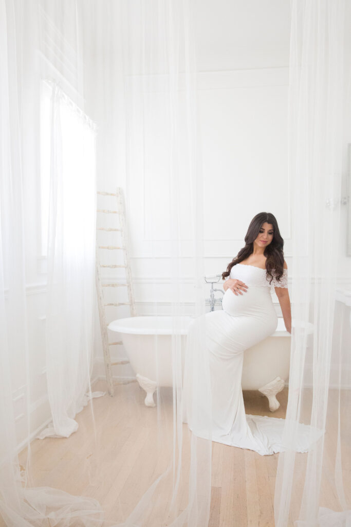 mom to be sitting on the edge of a bathtub at stardust studious Maternity Photoshoot locations in Miami