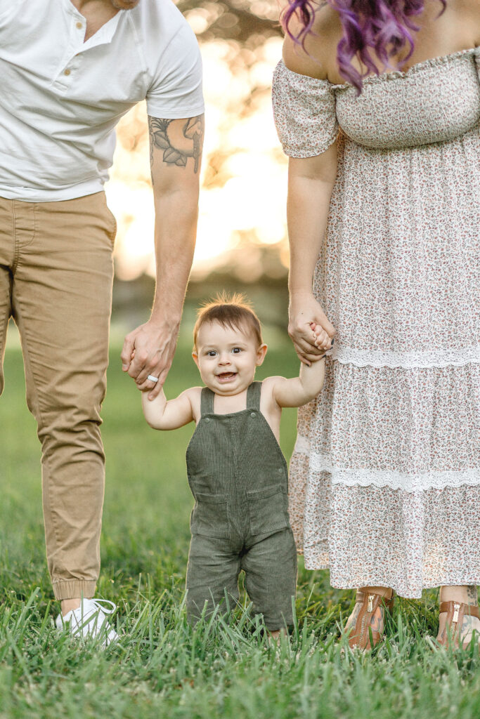 little boy smiling and holding his parents hands at Robbins Lodge