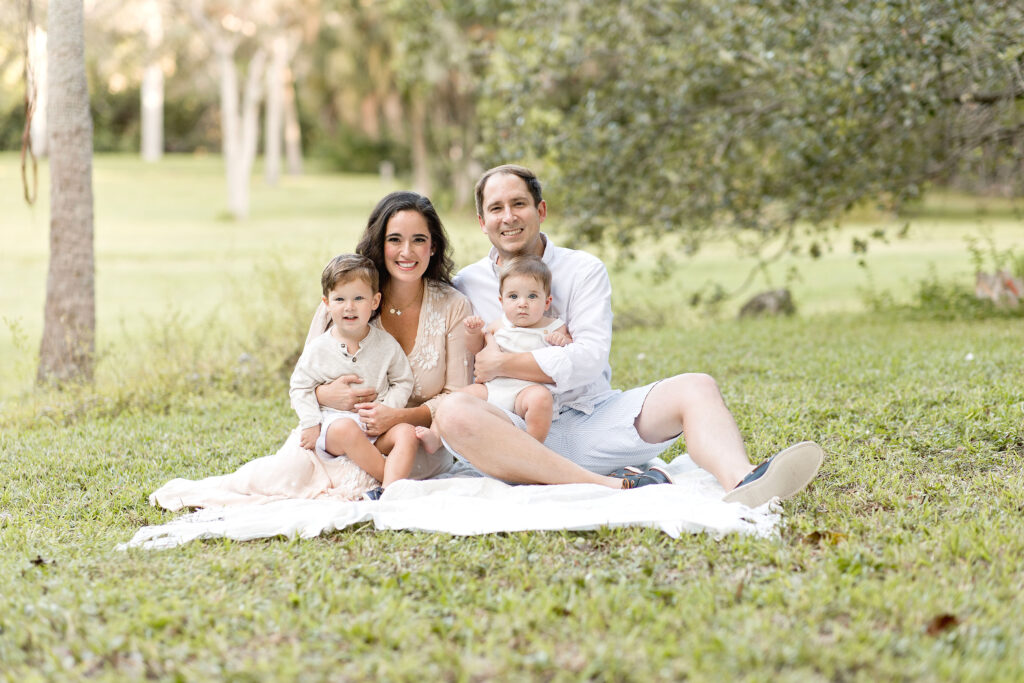 family of four sitting on a blanket in Matheson Hammock Park Maternity Photoshoot locations in Miami