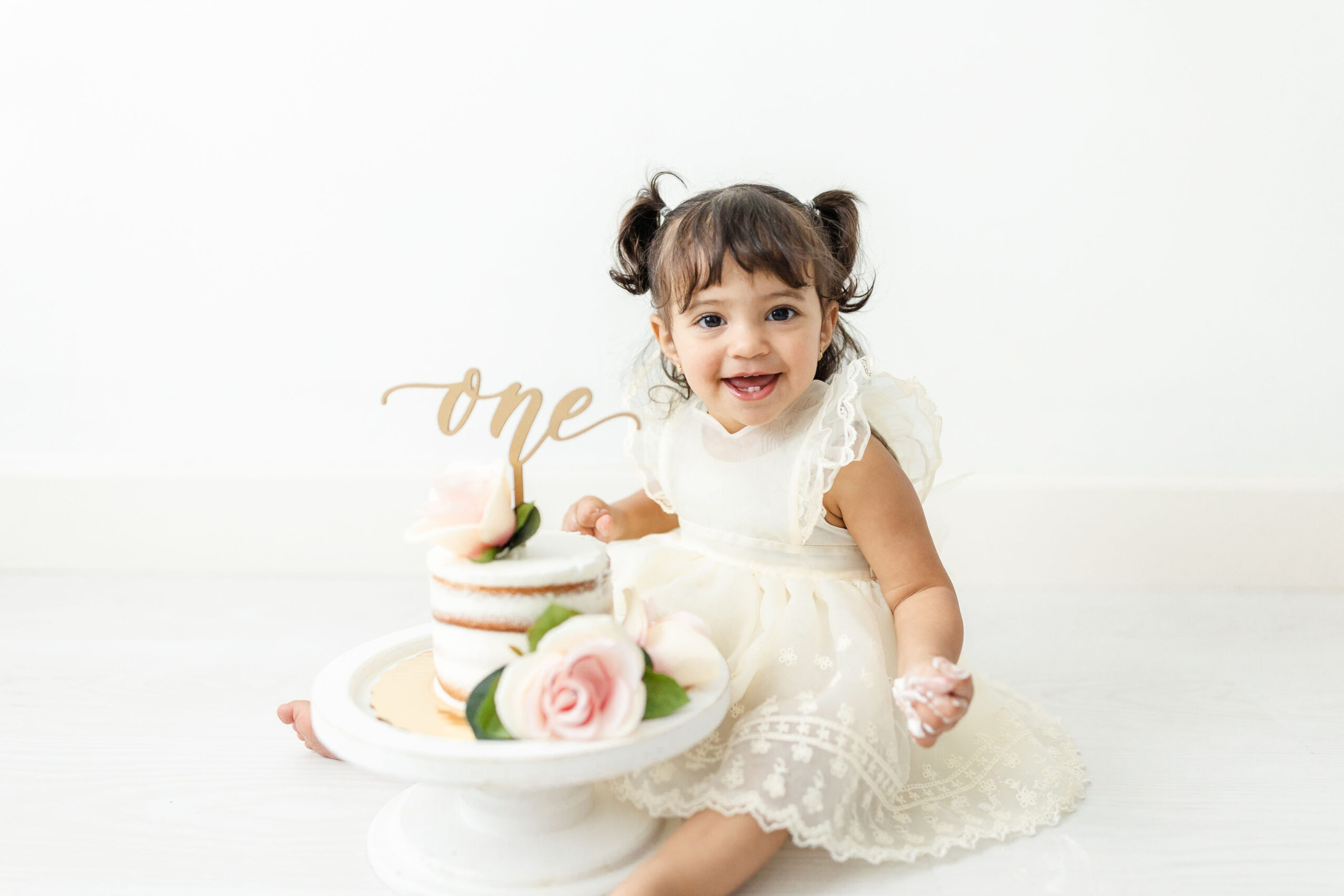 toddler girl happily smashes her 1st birthday cake in a studio Miami Nanny