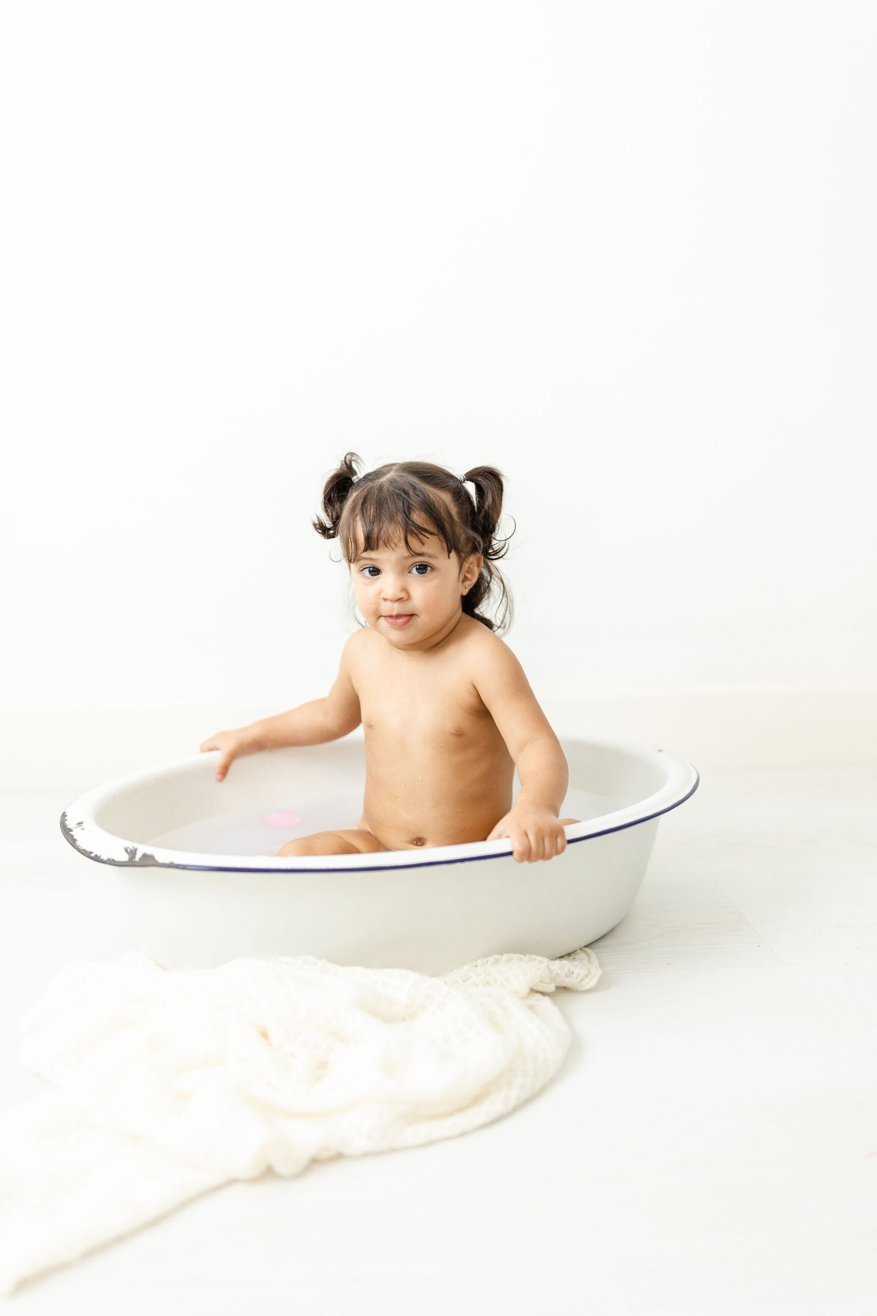 toddler girl sits in a wash bucket in a studio Miami Nanny