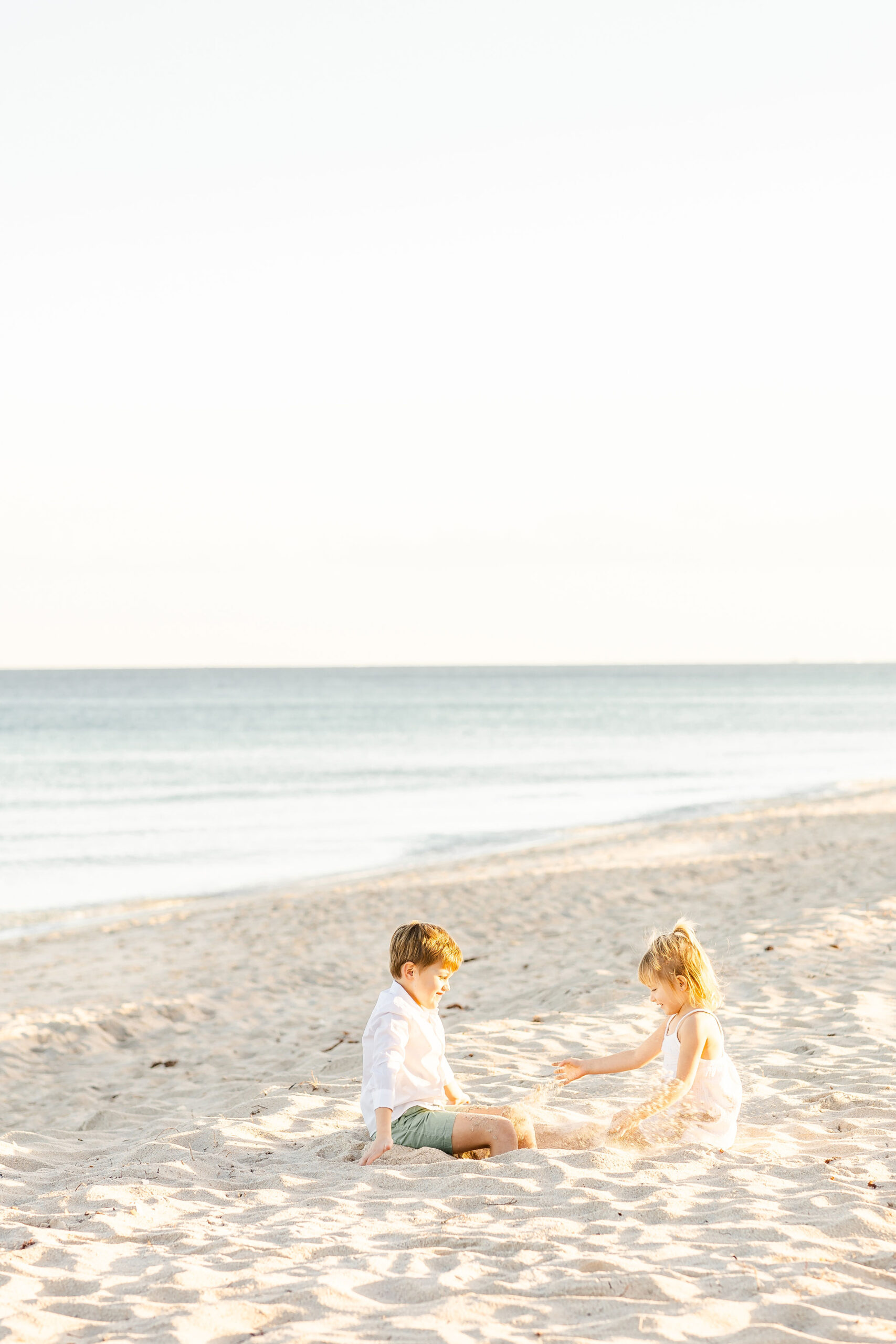 Boy and girl siblings play in the sand on a beach happy monkey shop