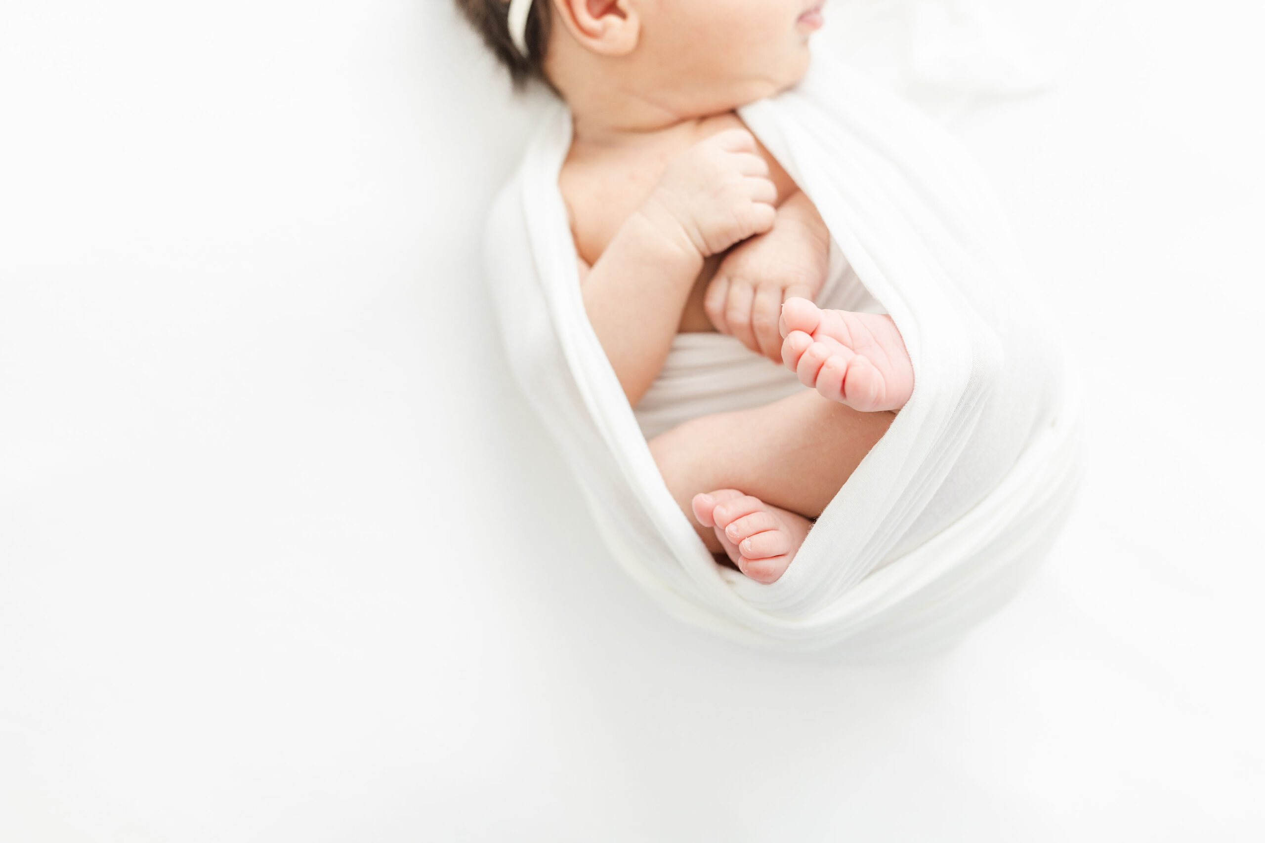 Details of a newborn baby sleeping in a white swaddle natural birth choices
