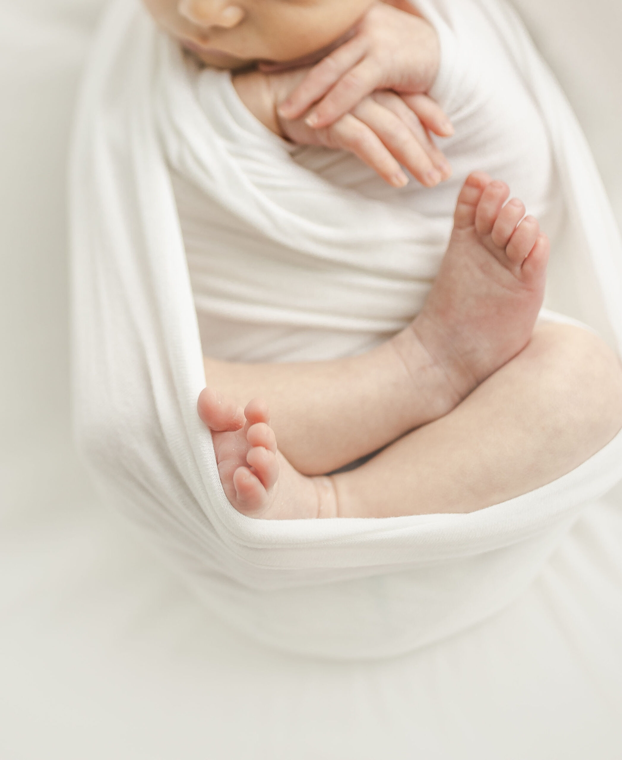 Details of a newborn baby sleeping in a white swaddle with feet and hands out your 4d baby miami