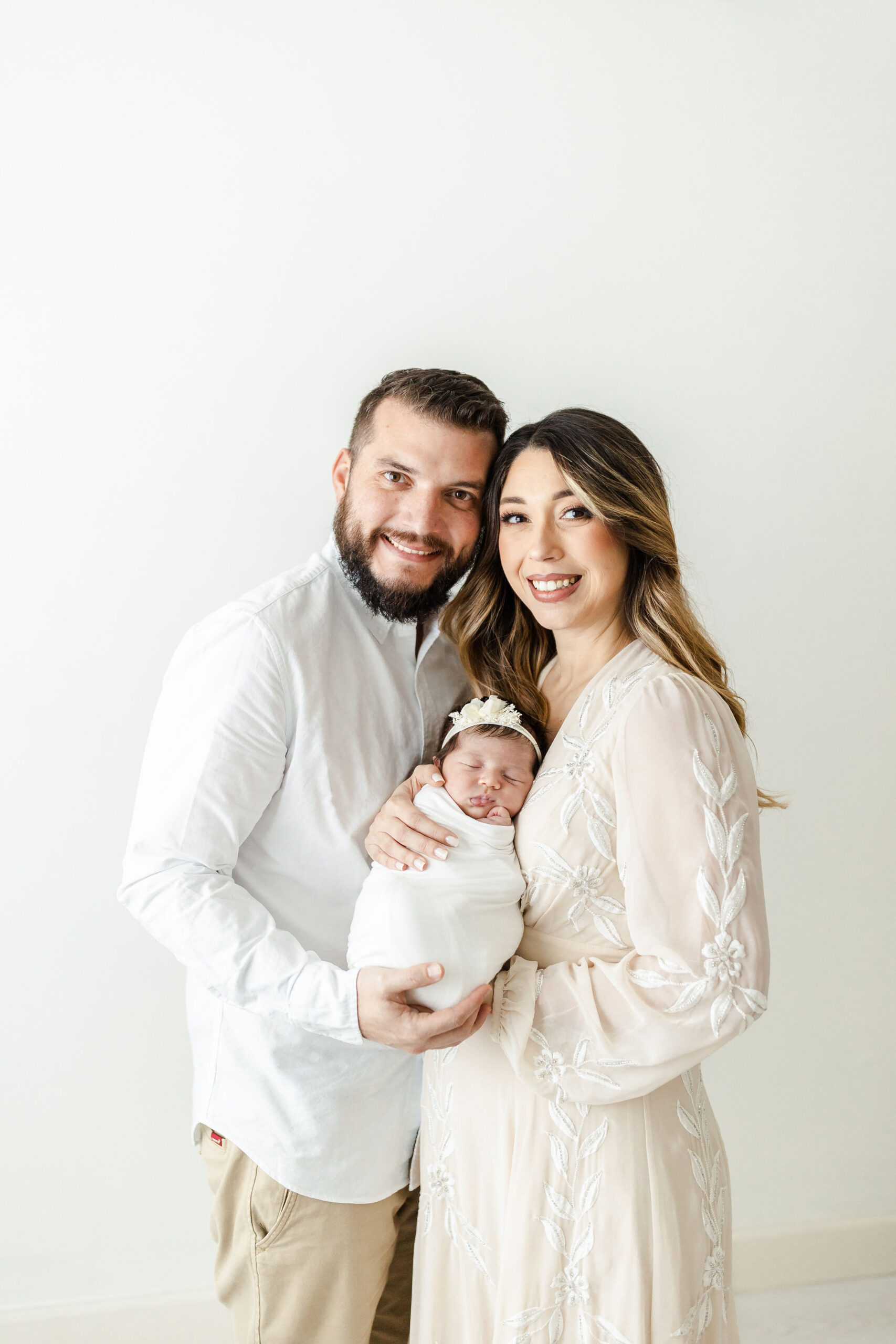 New parents stands in a studio holding their newborn daughter together the gathering place miami