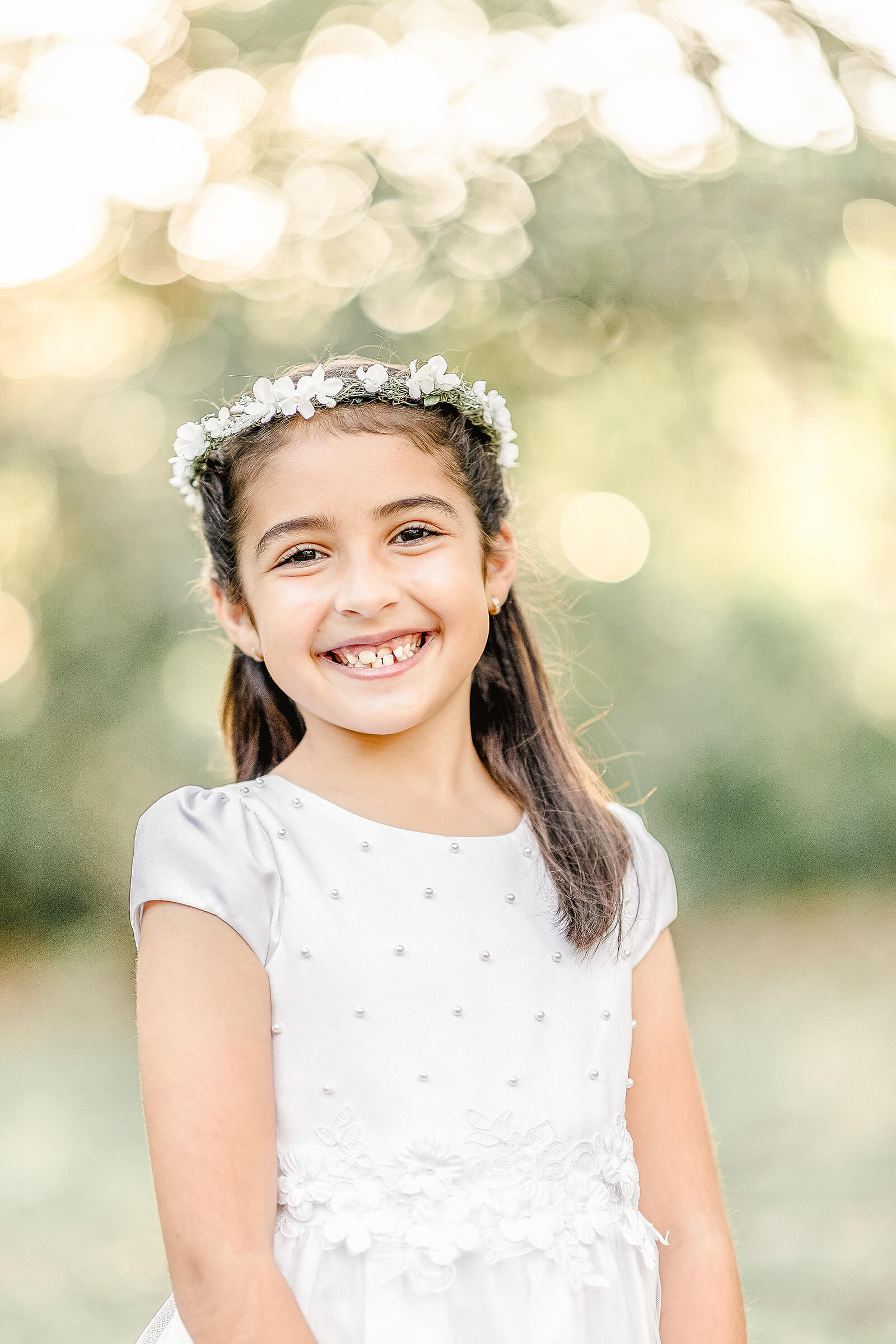 girl in all white communion dress and flower crown smiling for miami communion photographer