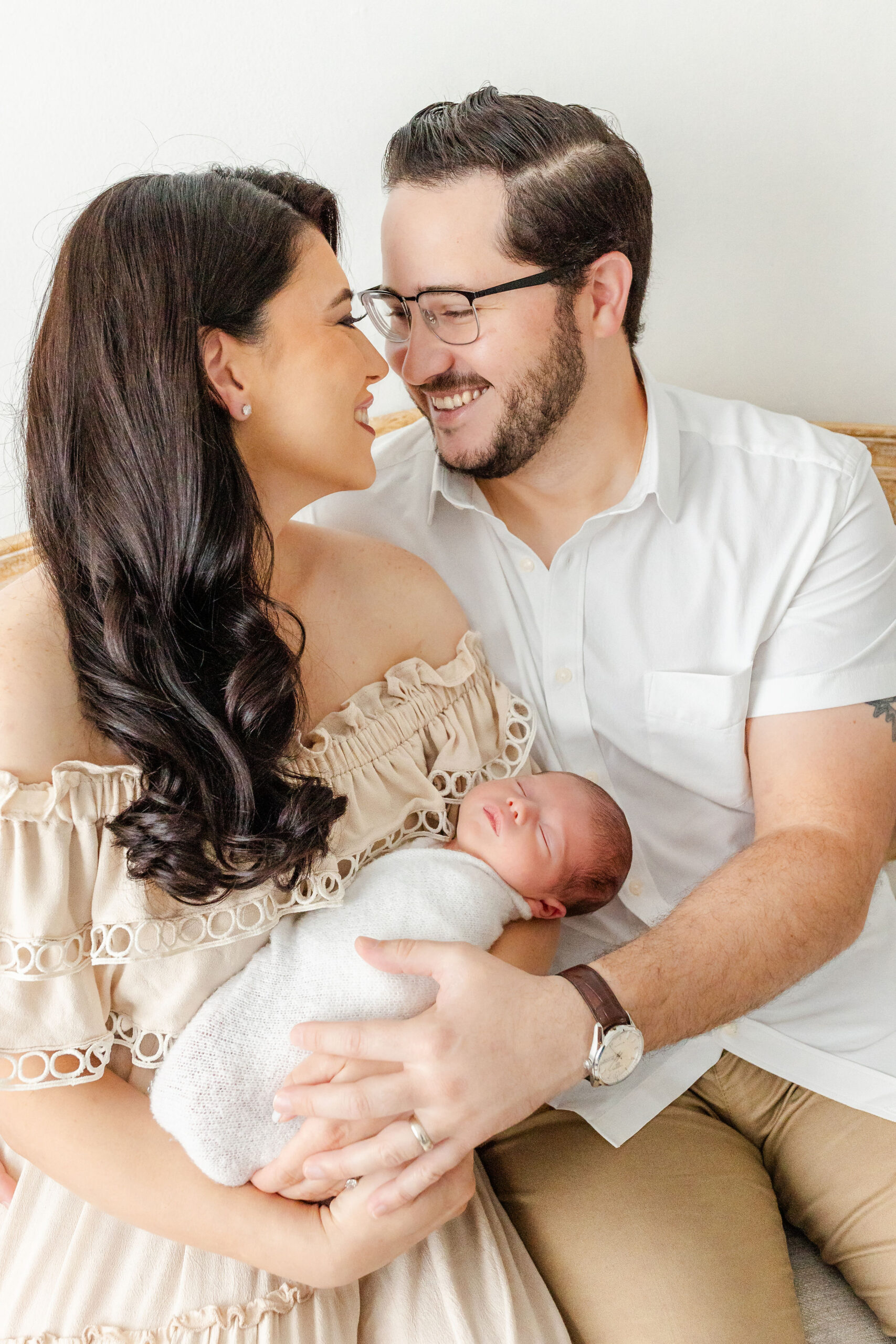 Happy new parents snuggle on a bench holding their sleeping newborn baby after visiting bambi baby store