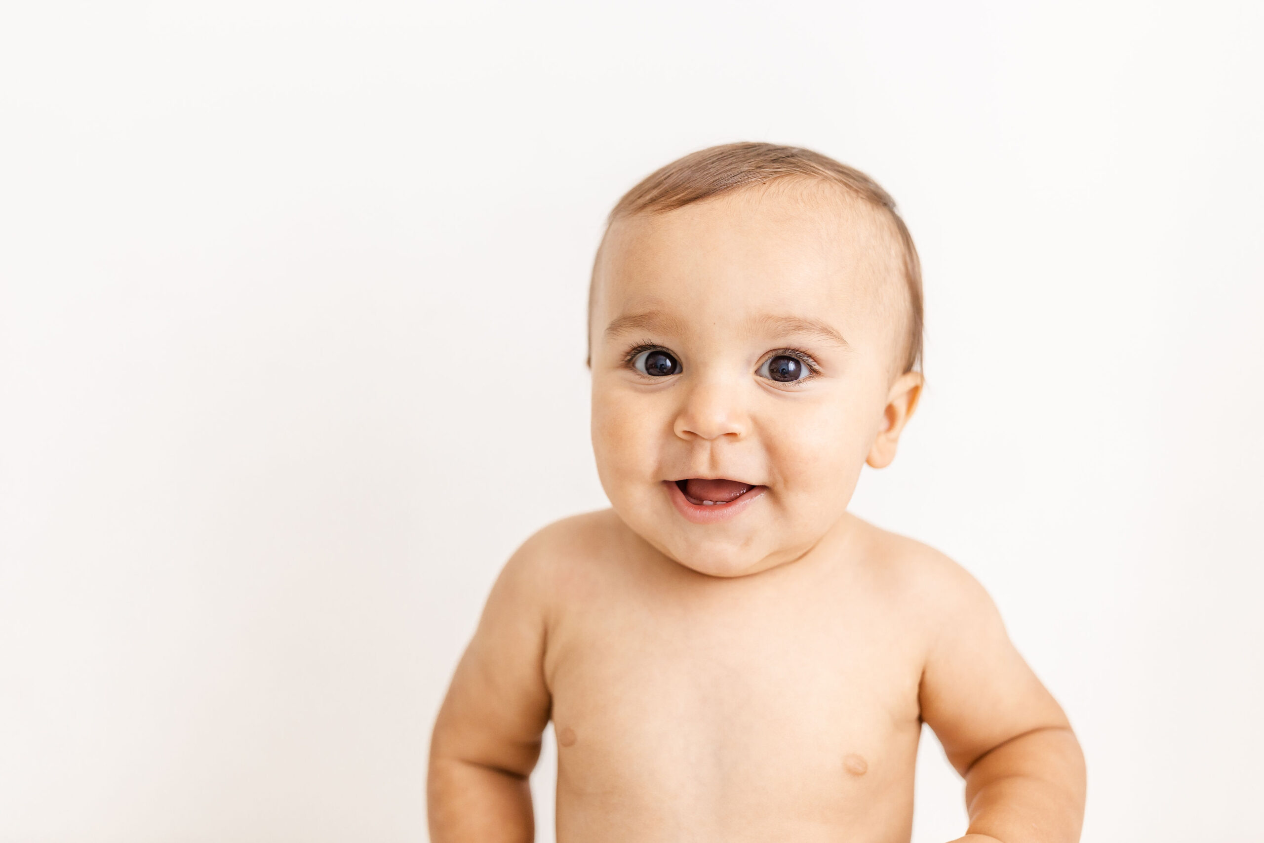 A happy smiling baby in a studio after meeting a nanny agency in fort lauderdale