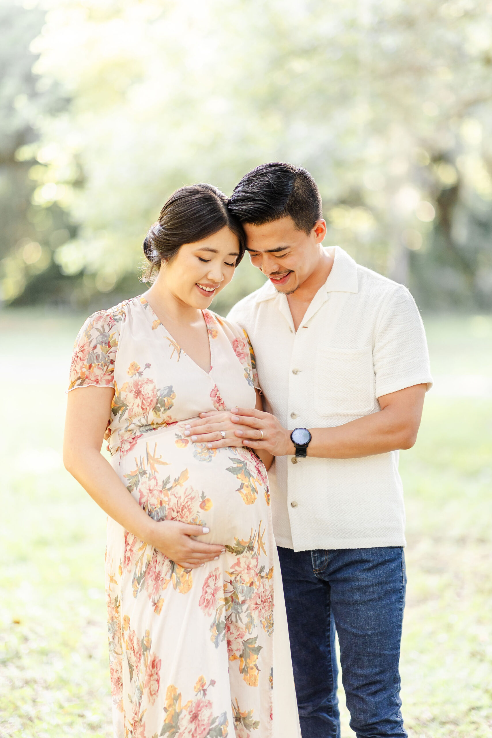 Happy expecting parents snuggle and hold the bump in a field touching foreheads after some prenatal yoga in fort lauderdale