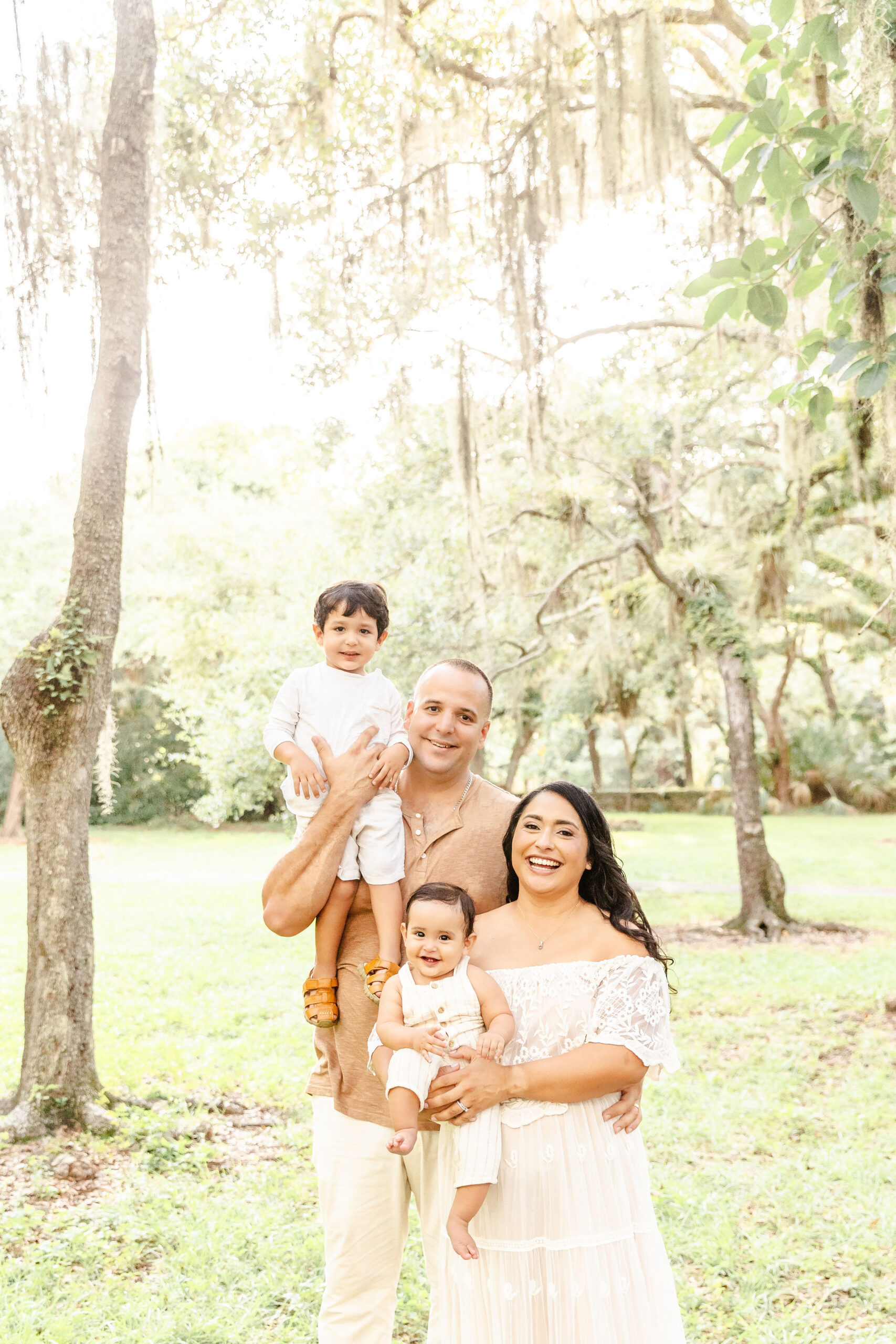 A happy family smiles with two toddlers in a park