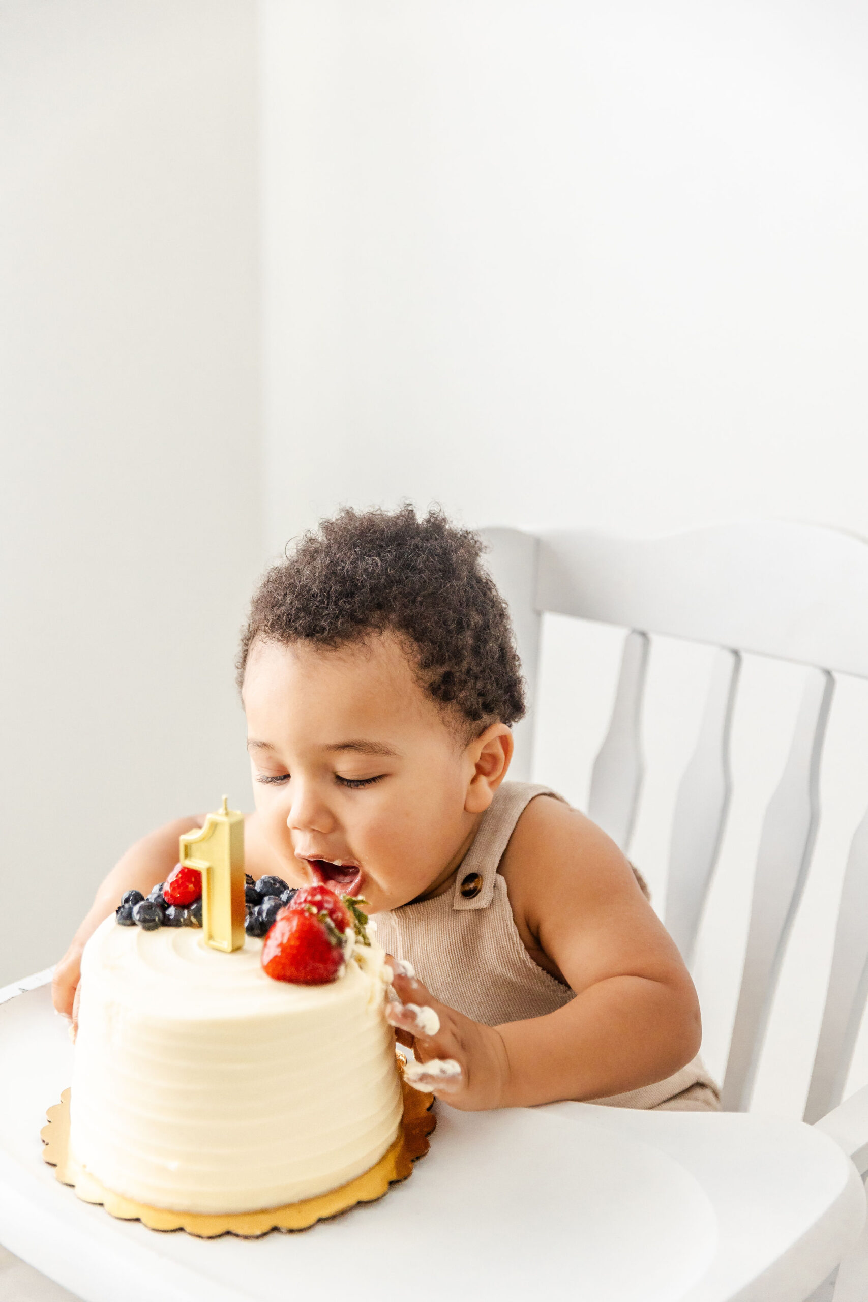An infant reaches for a big bite of a first birthday cake topped with fruit before heading to birthday party places in fort lauderdale