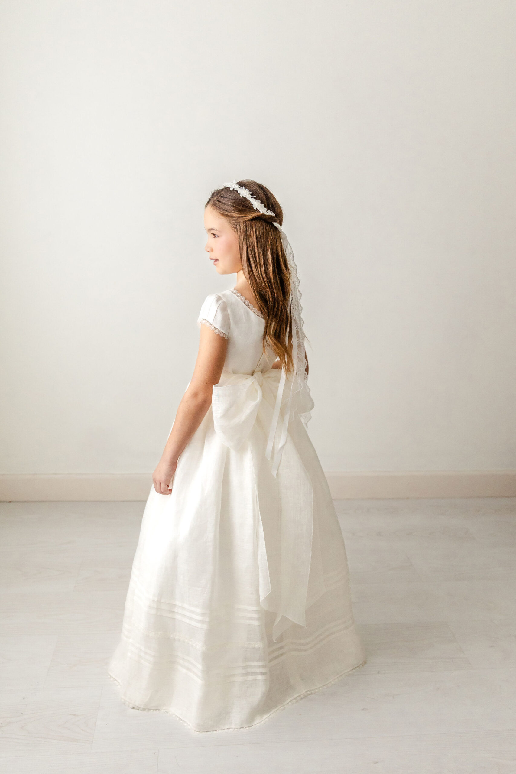 A young girl twirls in a white gown in a studio after finding fabulous first communion dresses in miami