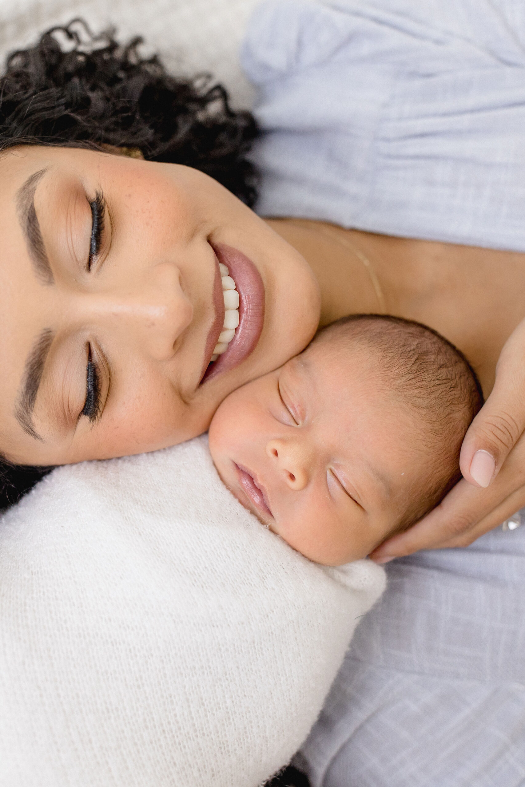 A newborn baby sleeps with her newborn baby against her cheek in a white swaddle after meeting lactation consultants in coral gables