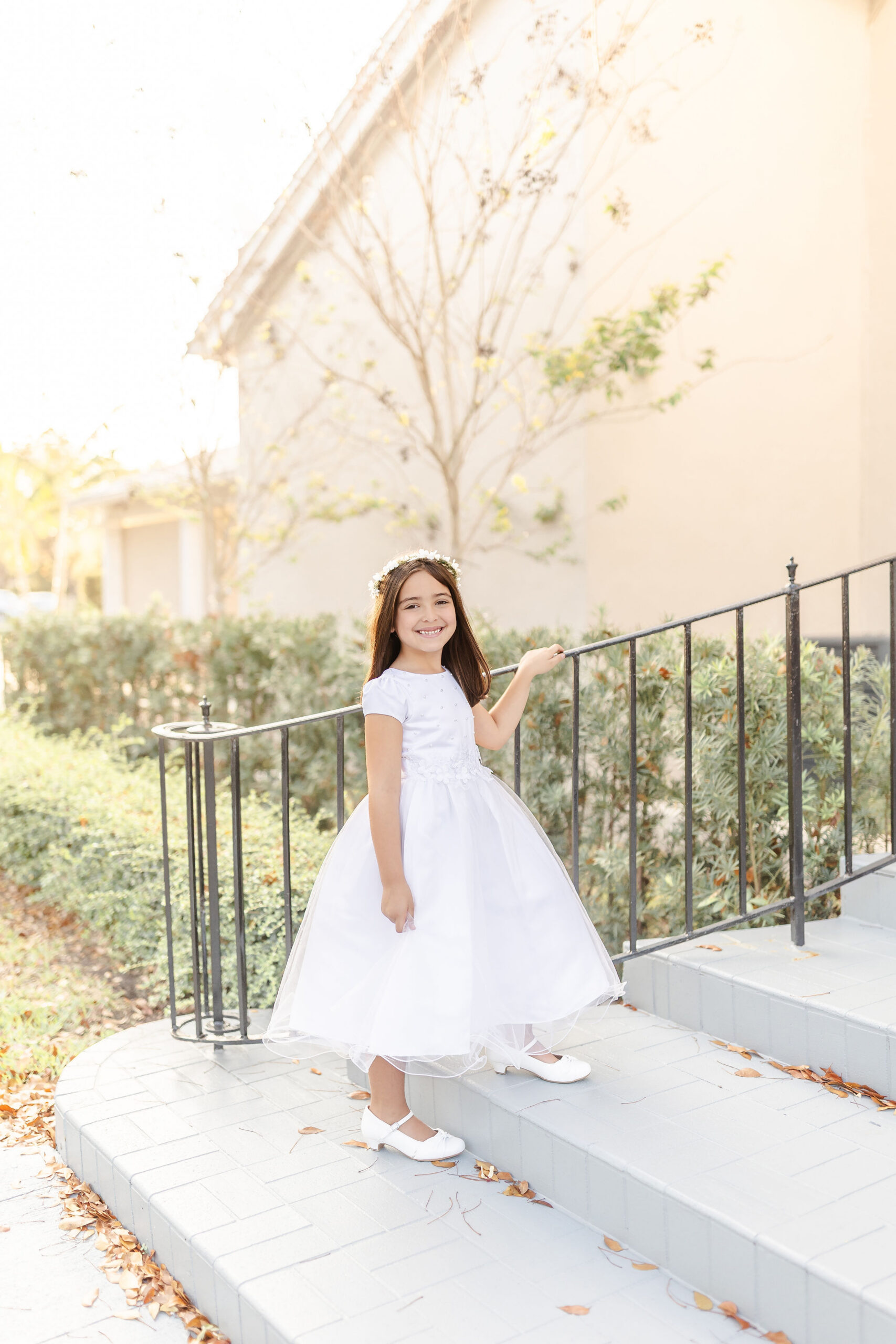 A young girl walks up the church steps in a white dress and flower headband after some great vacation bible school in miami
