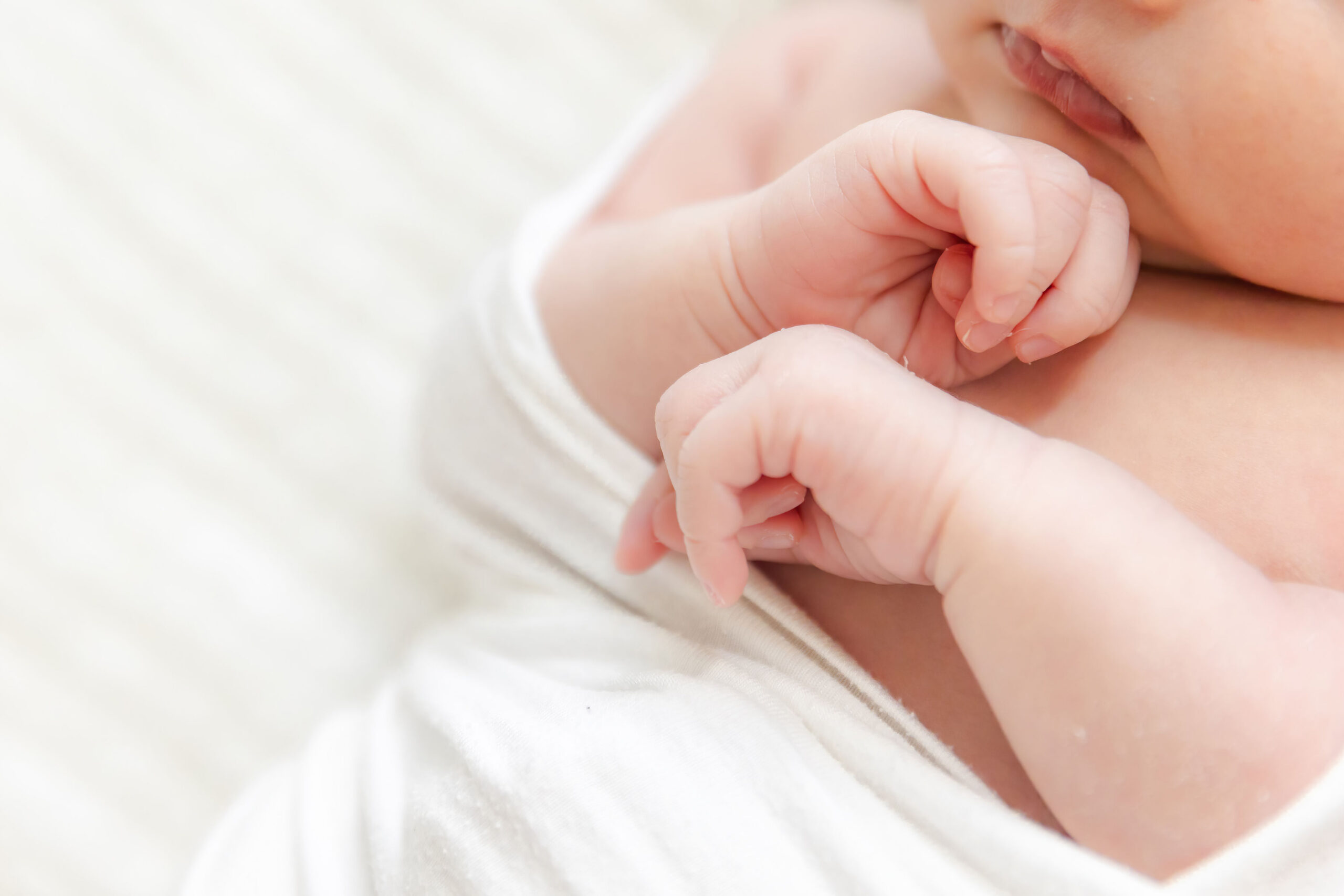 Details of a newborn baby's hands against her chest while sleeping